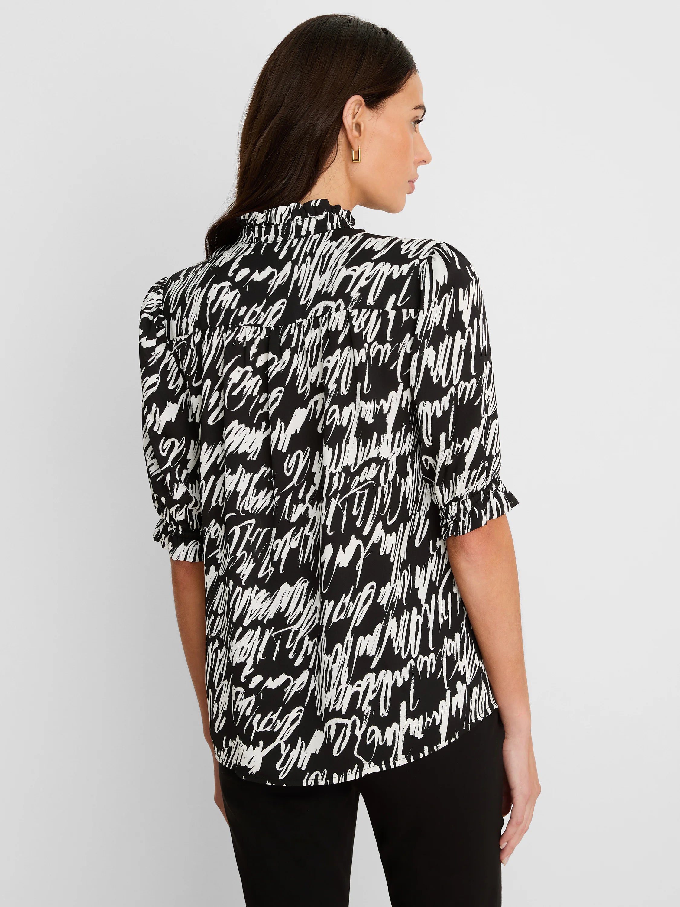 Black and white top with abstract cursive pattern, high ruffled neck, and gathered short sleeves.