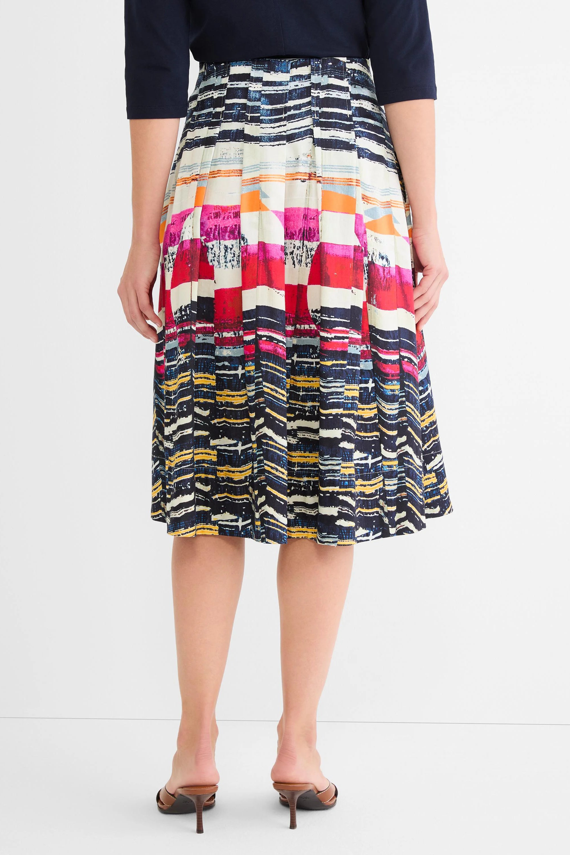 Pleated midi skirt with an abstract multi-color pattern of pink, red, orange, blue, yellow, and white blocks.