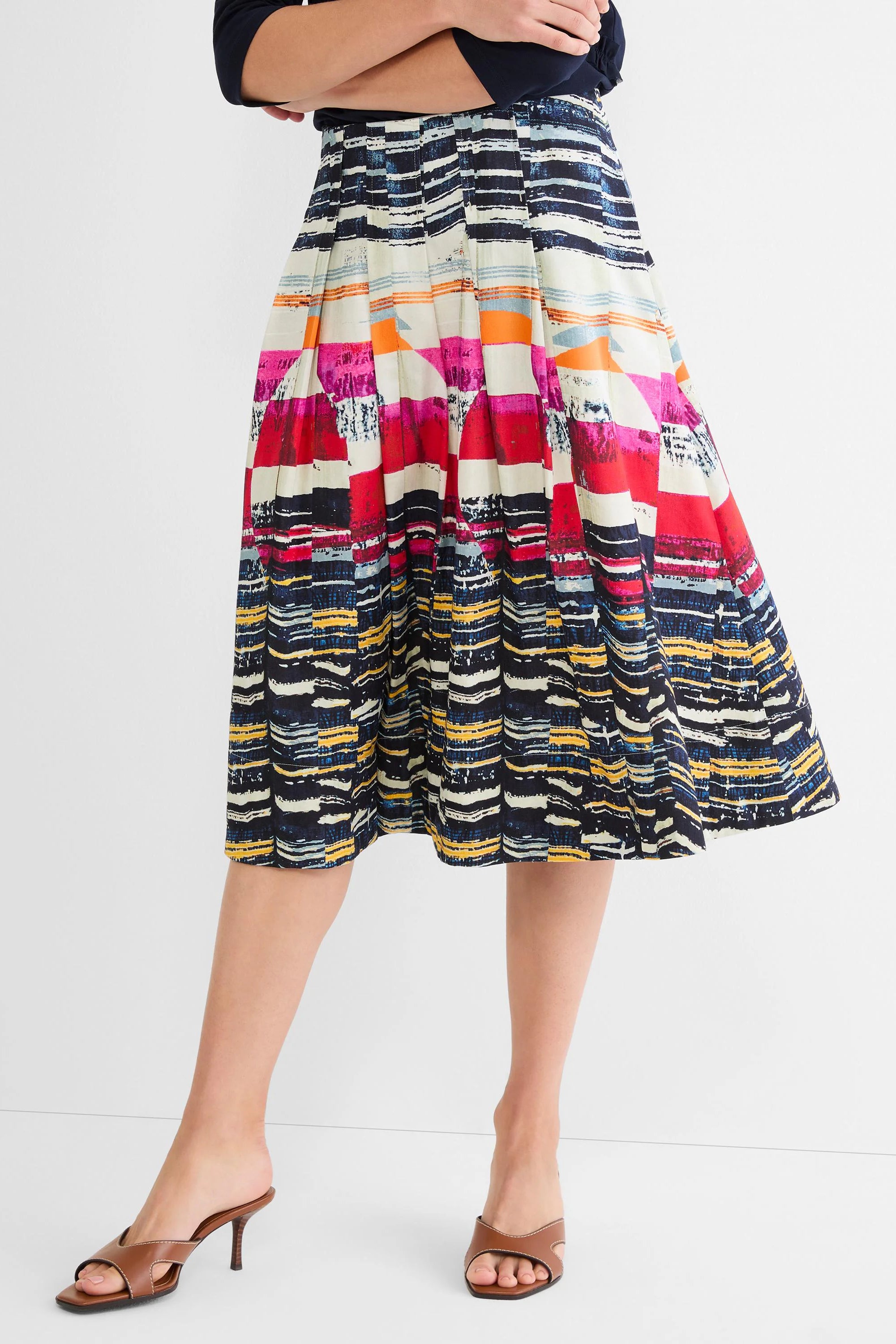 Pleated A-line midi skirt with abstract horizontal stripes in navy, white, red, pink, orange, and yellow.