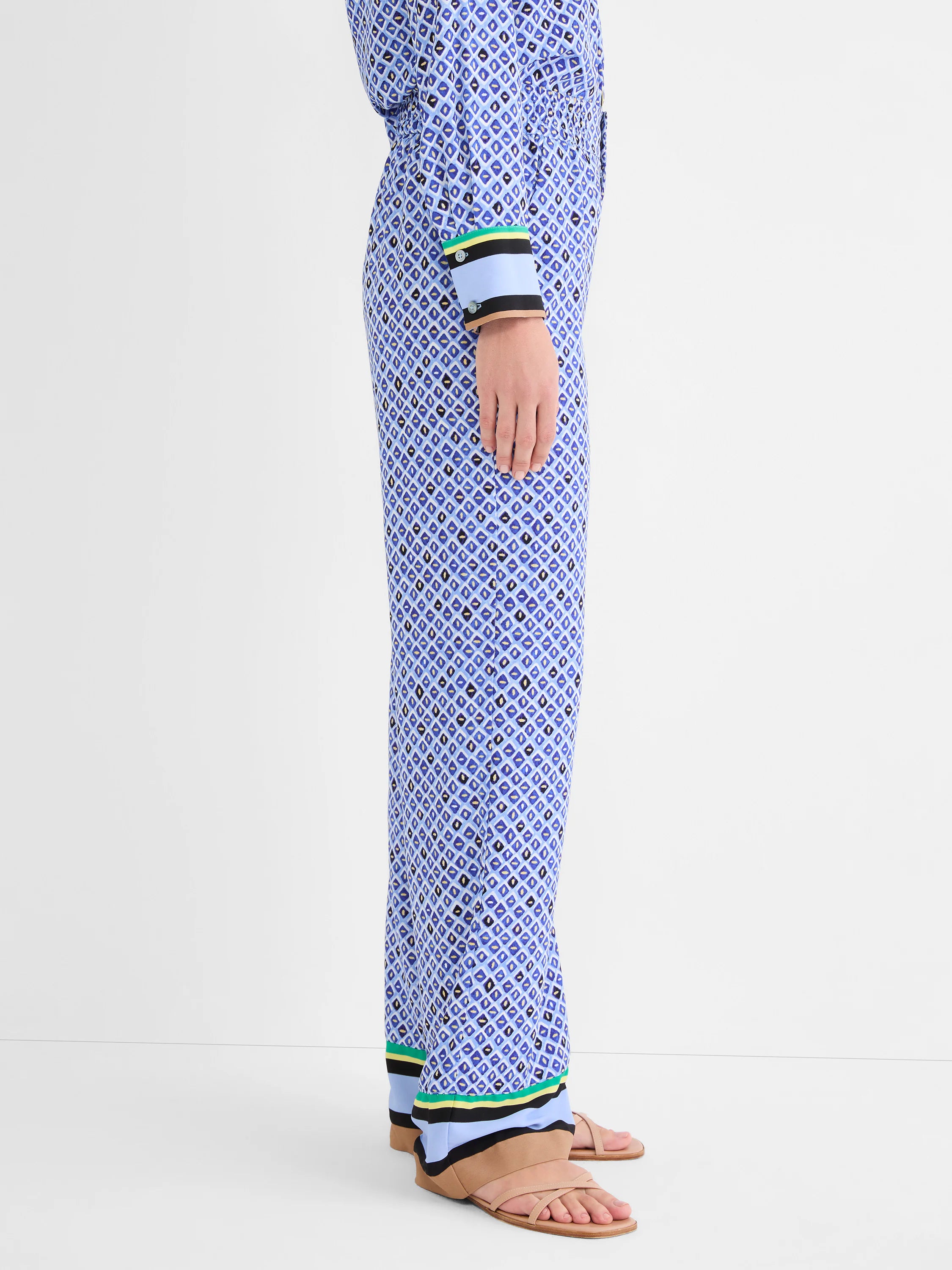 Wide leg pants, blue mosaic pattern with black/gold accents. Hem has tan, light blue, black, green, yellow striped trim.
