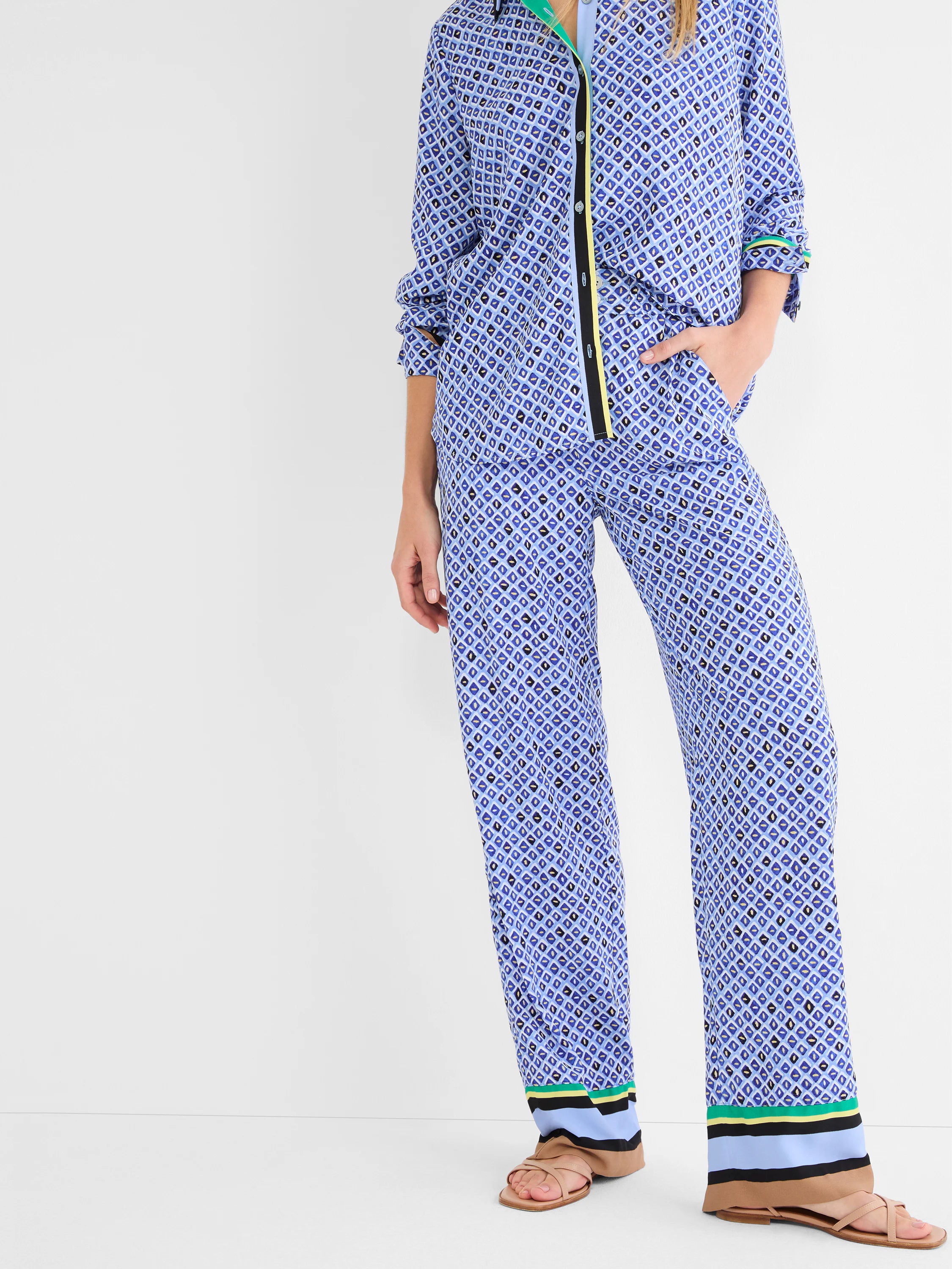 Blue wide-leg pants feature mosaic pattern of blues, black, white, gold. Striped hem trim: black, blue, yellow, green.