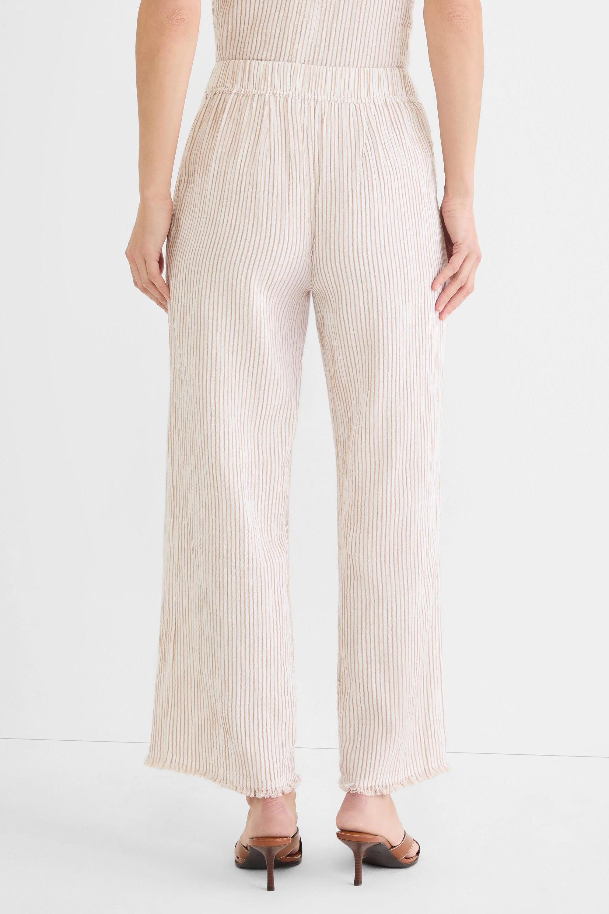 Cream wide-leg pants with vertical tan pinstripes, an elastic waist, and frayed hems.