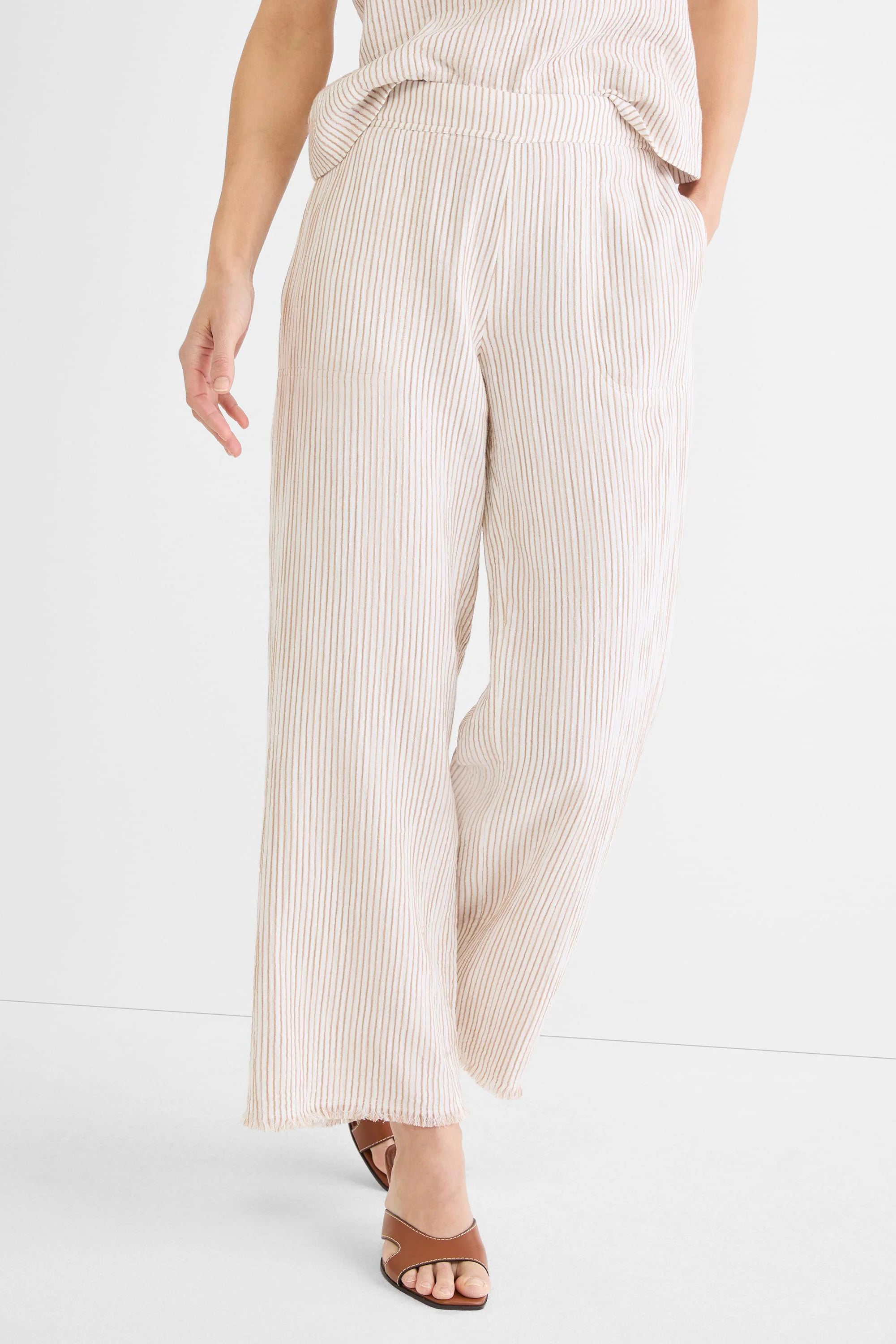 Off-white wide-leg pants with thin tan vertical pinstripes and a frayed hem.
