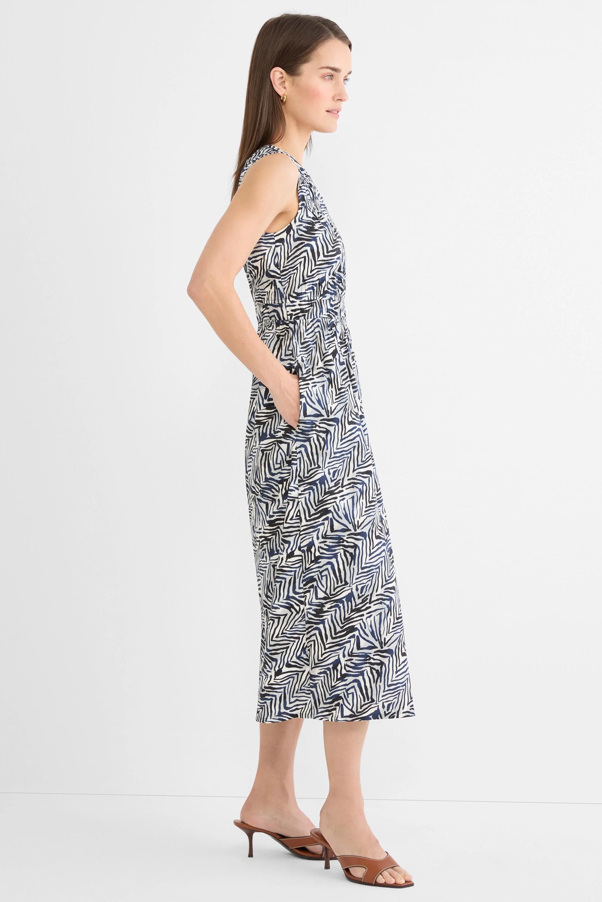 Sleeveless V-neck midi dress with elastic cinched waist and pockets. Features a cream, black, and navy abstract zig-zag...