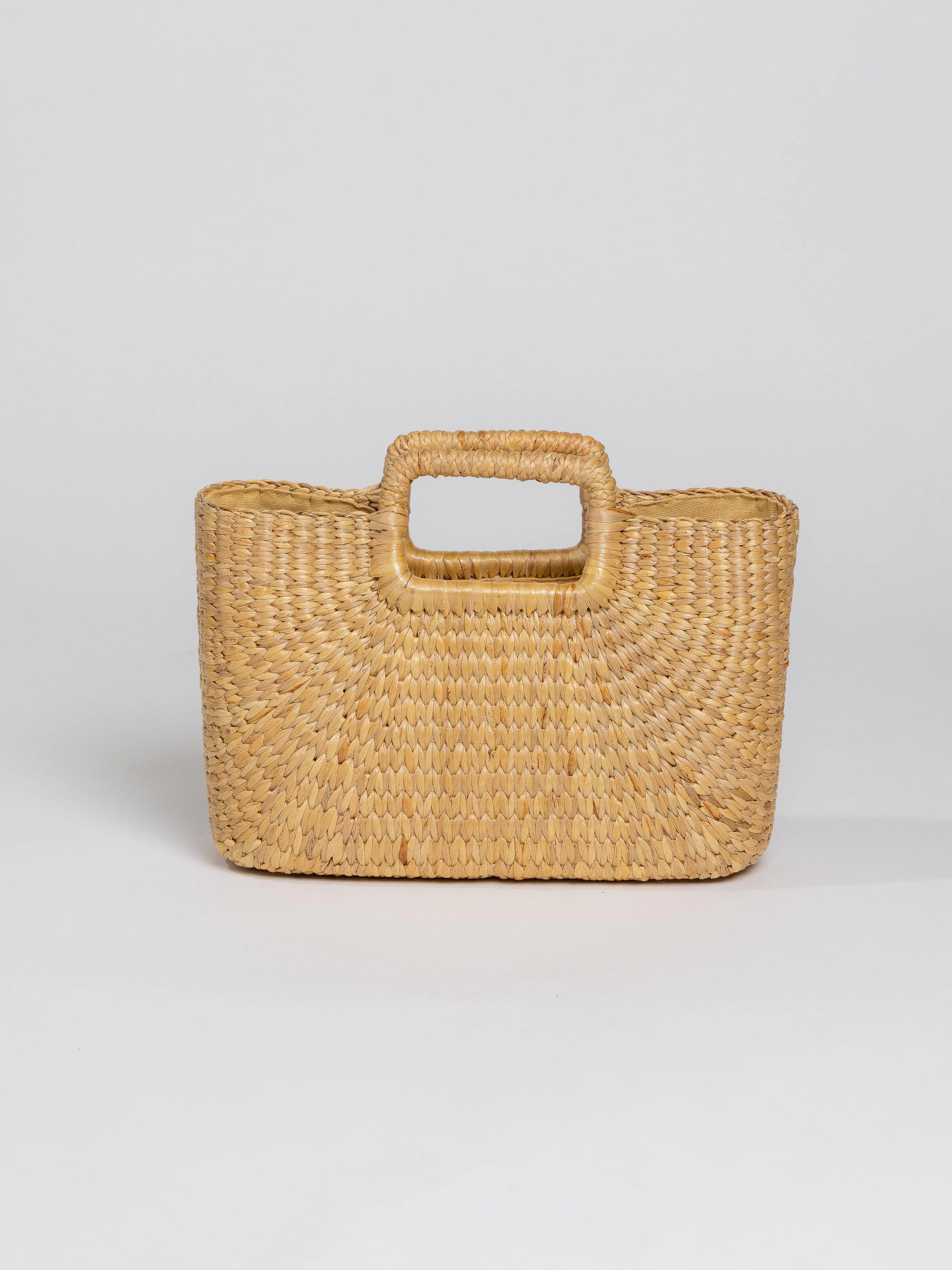 Rectangular light tan woven bag with a single, central integrated handle.