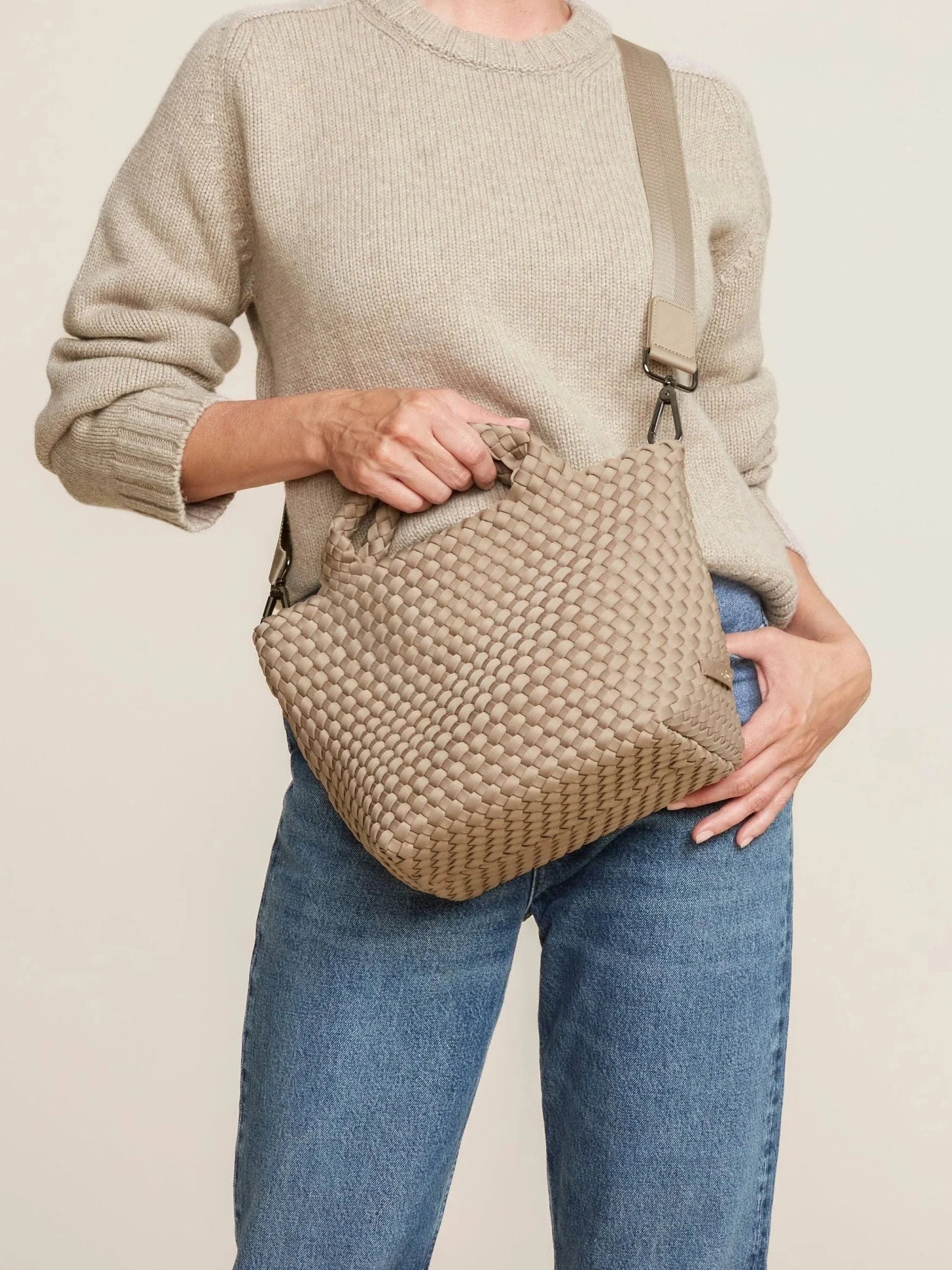 Beige woven tote with top handles & a detachable long strap, carried by a person.
