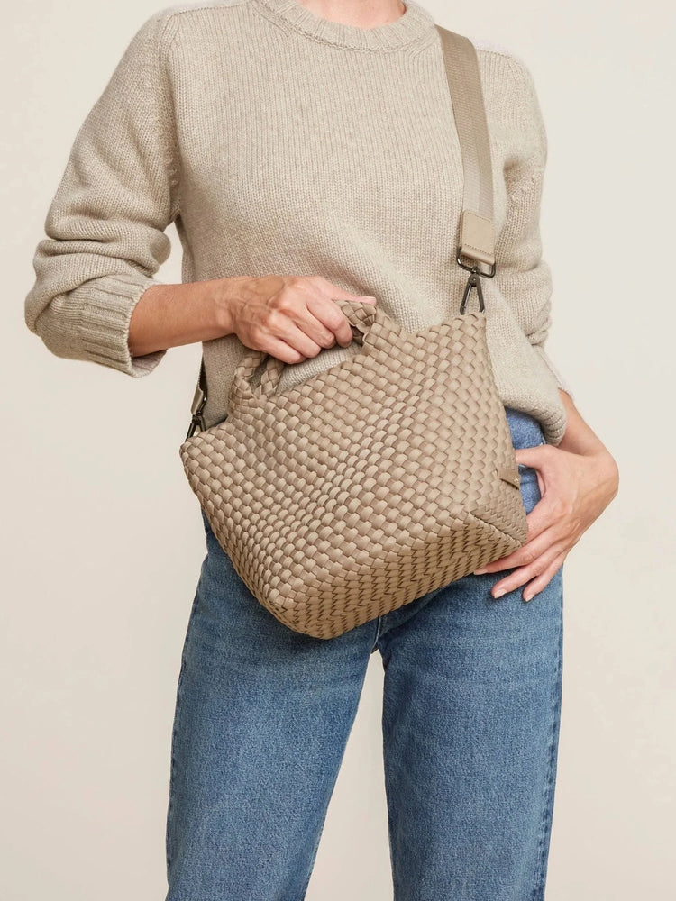 Beige woven tote with top handles & a detachable long strap, carried by a person.