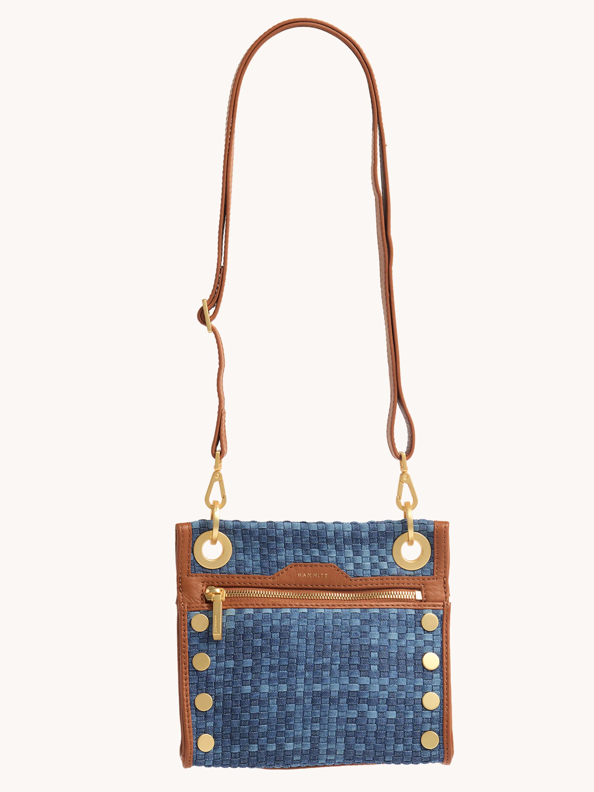 Small blue denim clutch with brown leather trim, gold zipper, and gold studs. Brown leather shoulder strap.