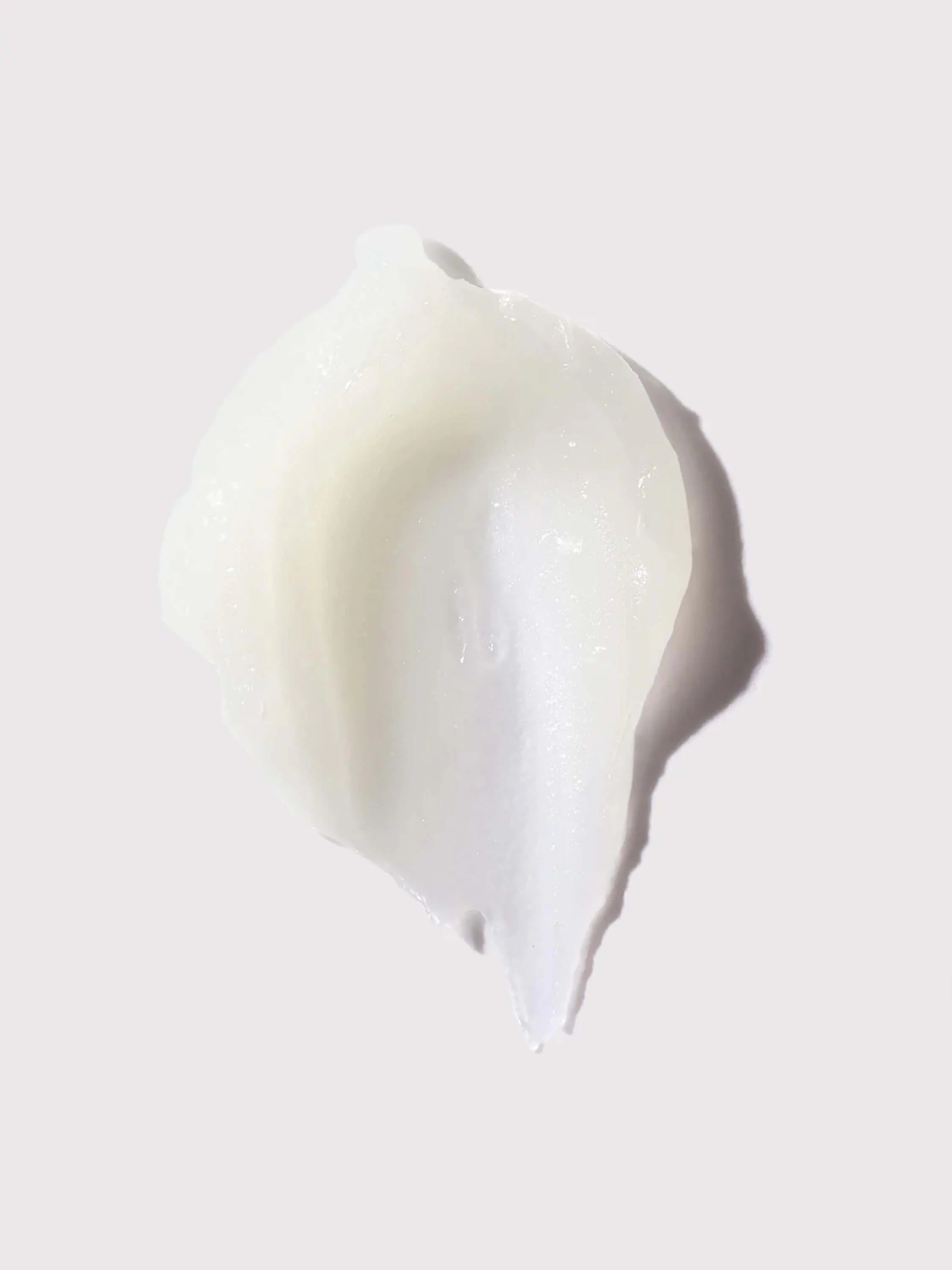 An irregular smear of thick, creamy off-white balm with a subtle sheen on a light background.