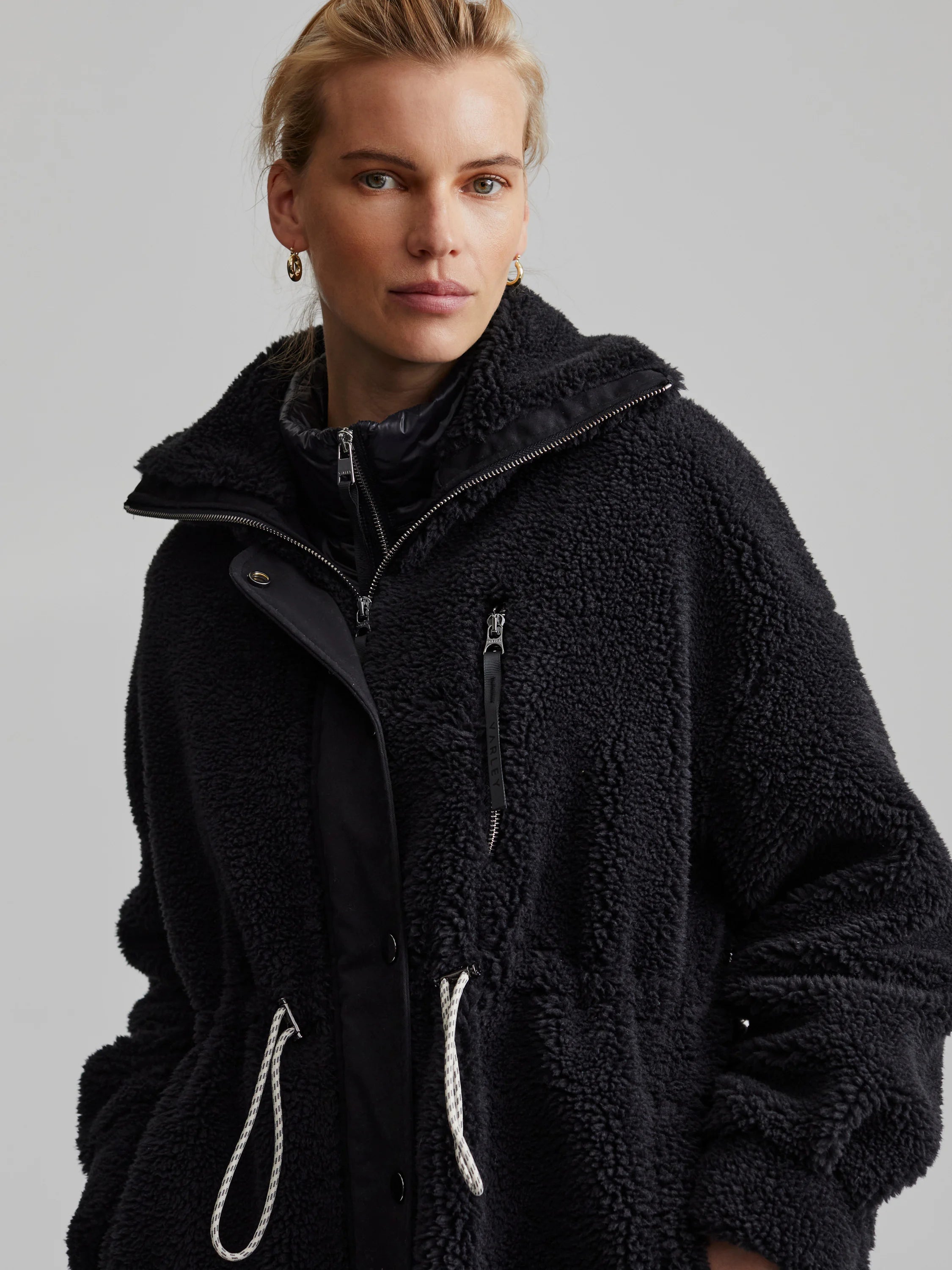 Black, textured fleece coat with a black liner, zipper, and drawstring waist. Features a hood.