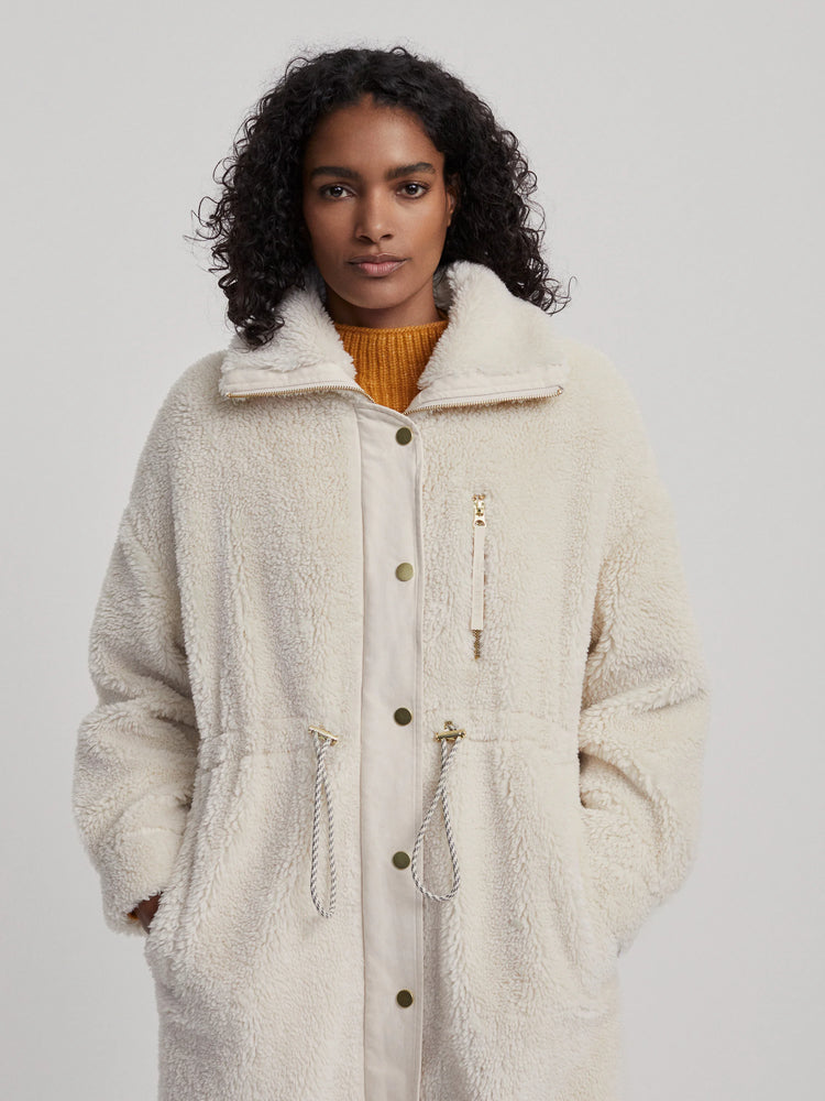 Off-white long teddy-style coat with gold zipper and buttons. Features drawstring waist.