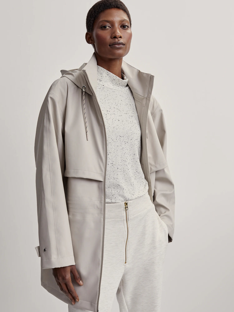 Light beige hooded raincoat, mid-length. Relaxed fit, drawstring hood, and adjustable snap cuffs.