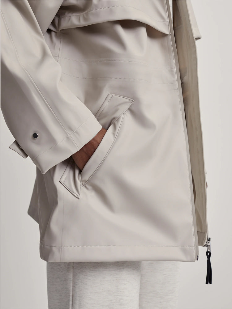 Stone Varley Alyssa Raincoat with a hand in a side pocket, visible stitching, and a black zipper pull.
