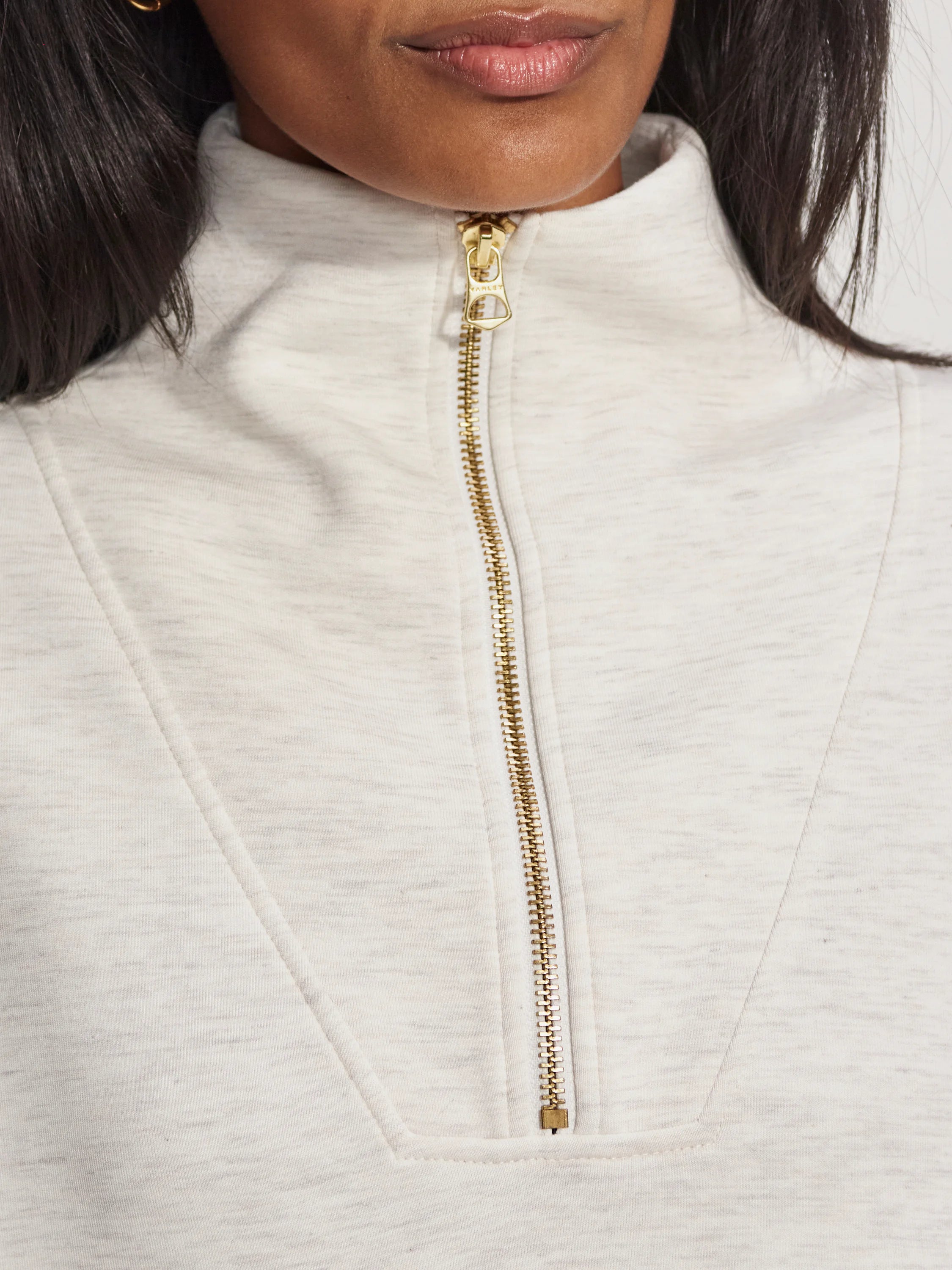 Off-white half-zip sweatshirt with gold zipper.
