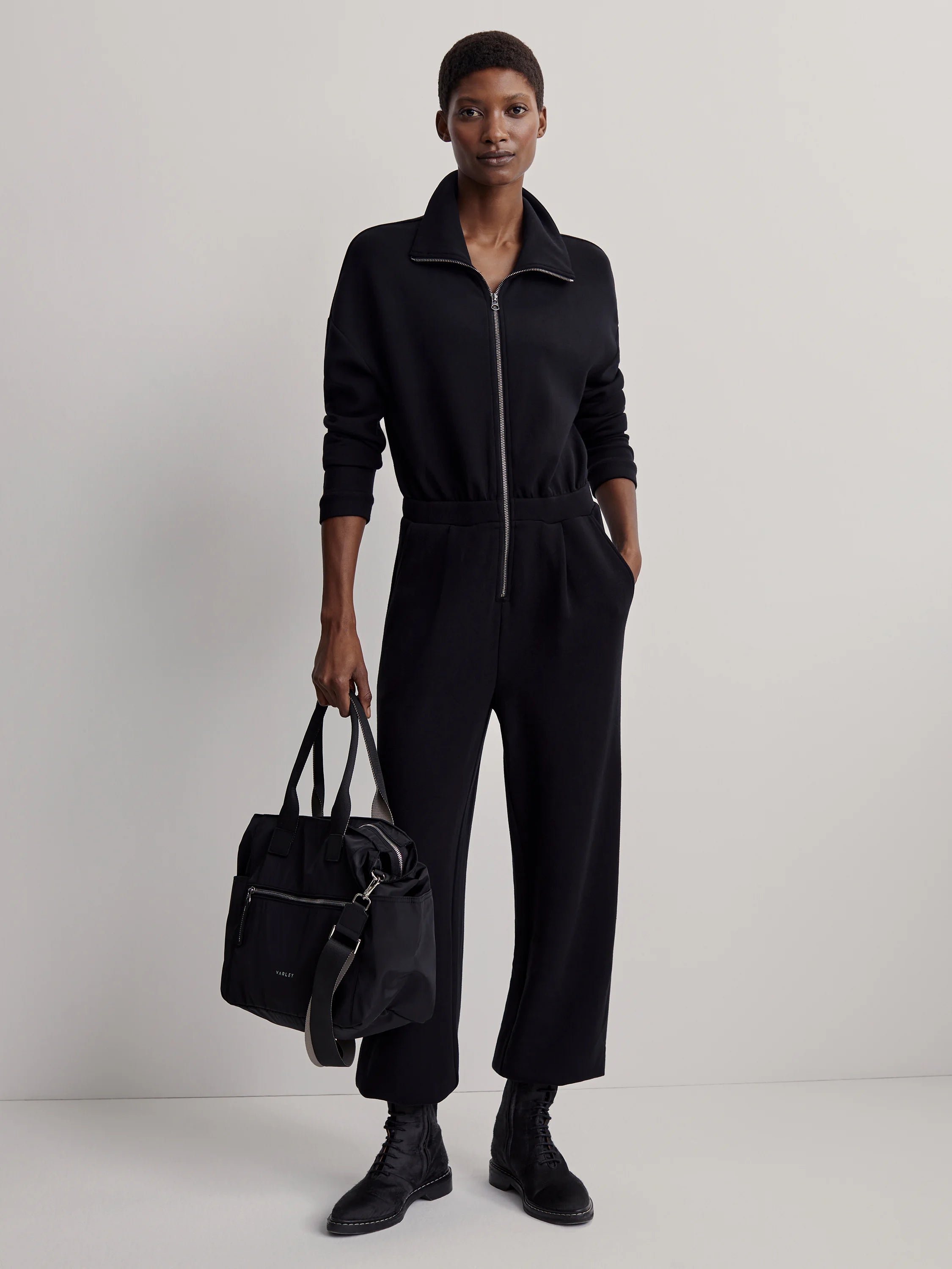 Black Varley Kelso Crossbody Bag. Tote style with top handles, a light grey-backed strap, and silver zip pockets.