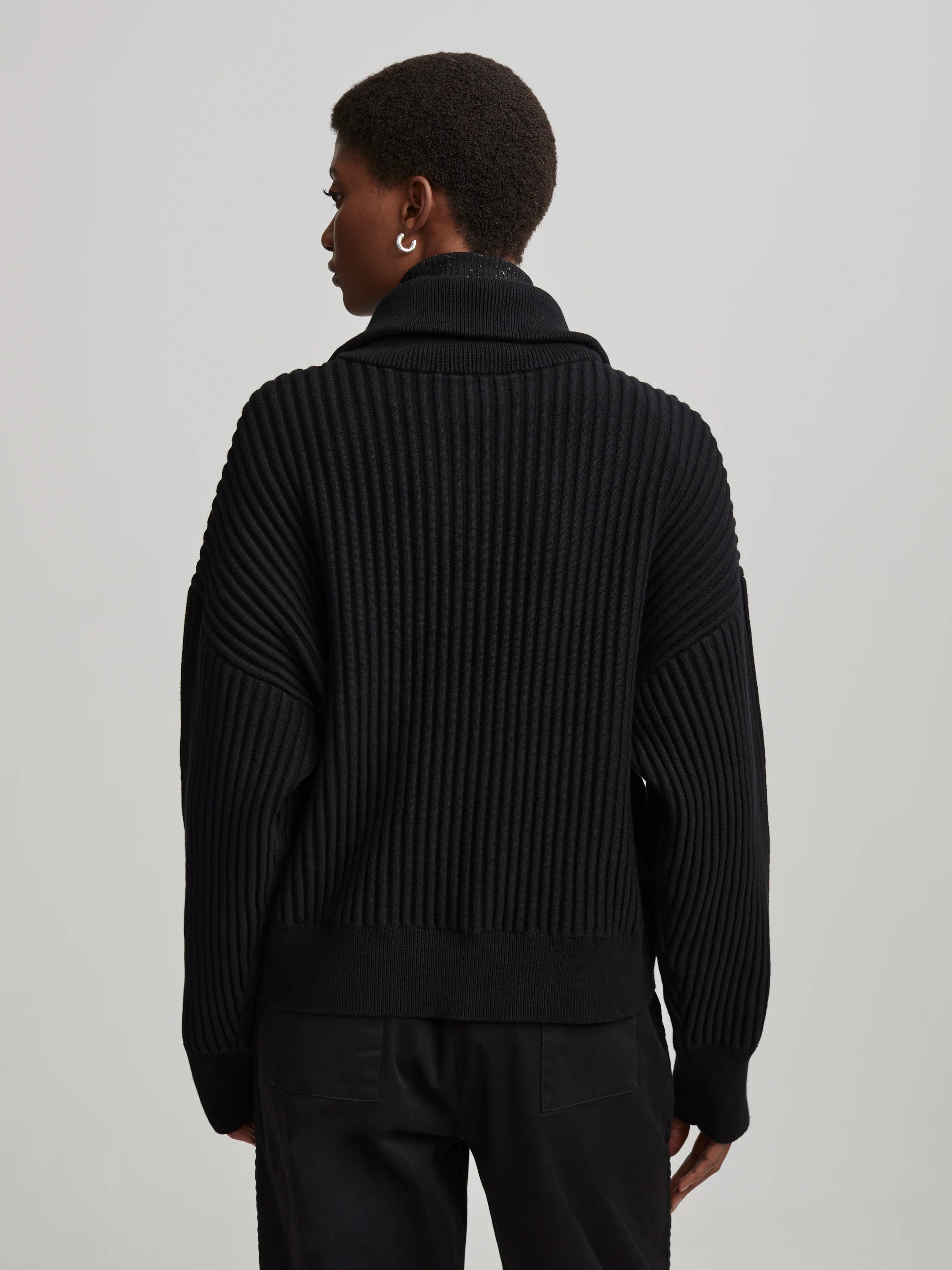 Black mock neck sweater with vertical ribbing and relaxed, dropped-shoulder fit, shown from the back.
