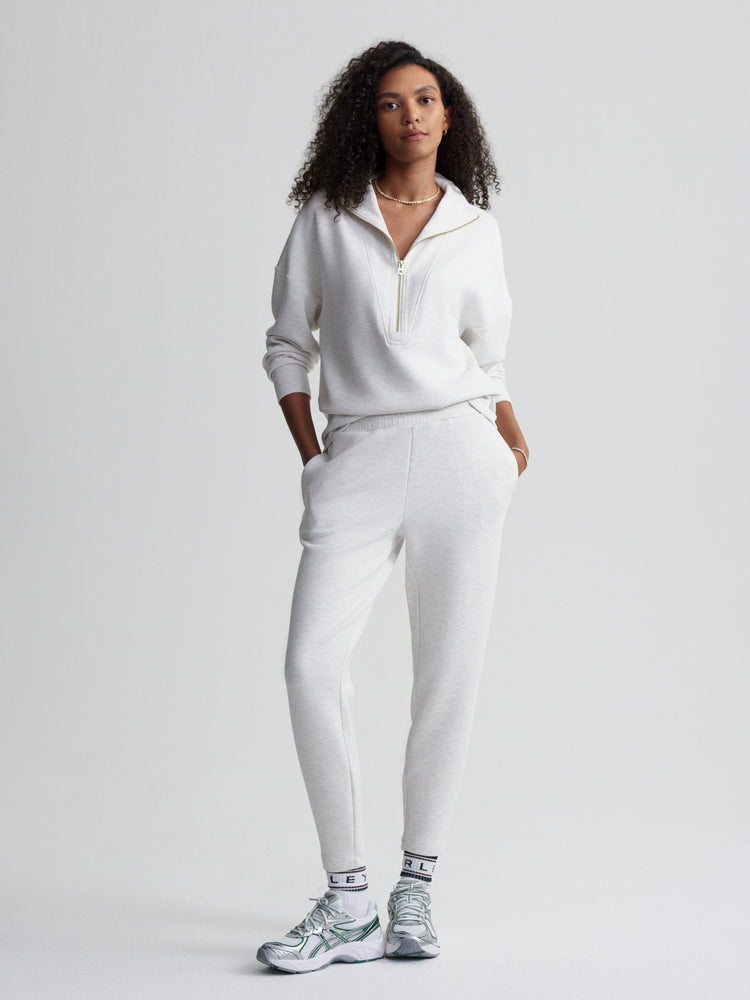A model poses in a light grey quarter-zip fleece pullover and matching slim jogger sweatpants.