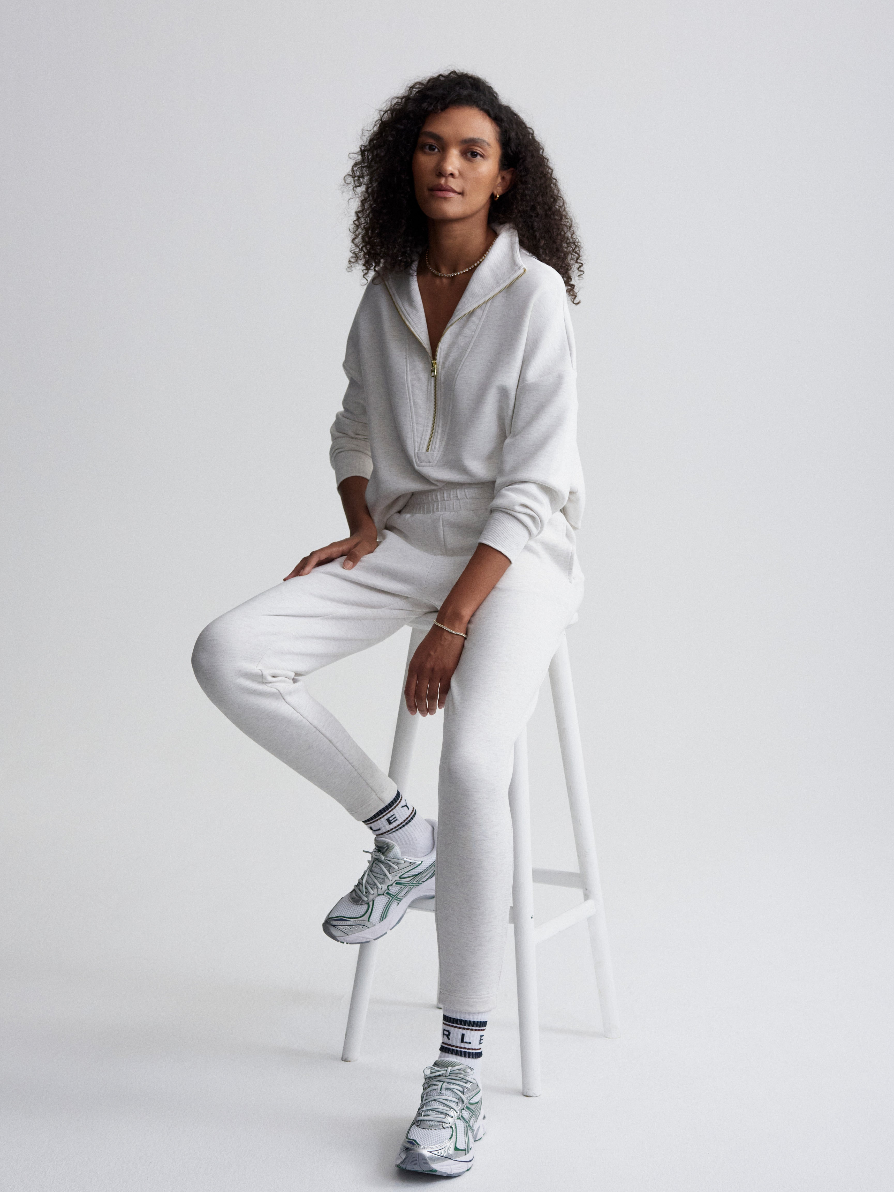 Model wears a relaxed heather grey quarter-zip pullover and tapered jogger sweatpants loungewear set.