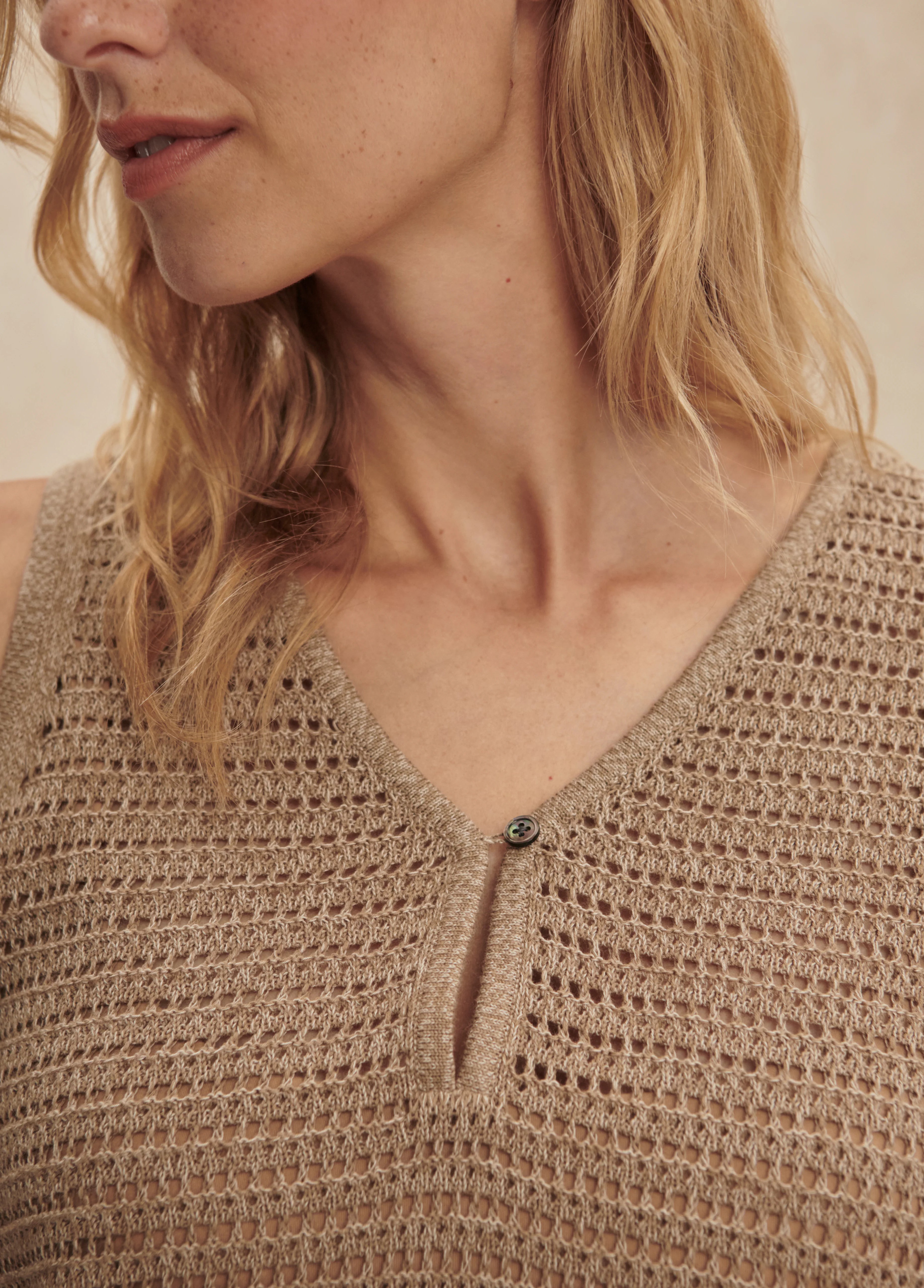 Tan open-knit V-neck tank with a perforated pattern and a single dark iridescent button closure.