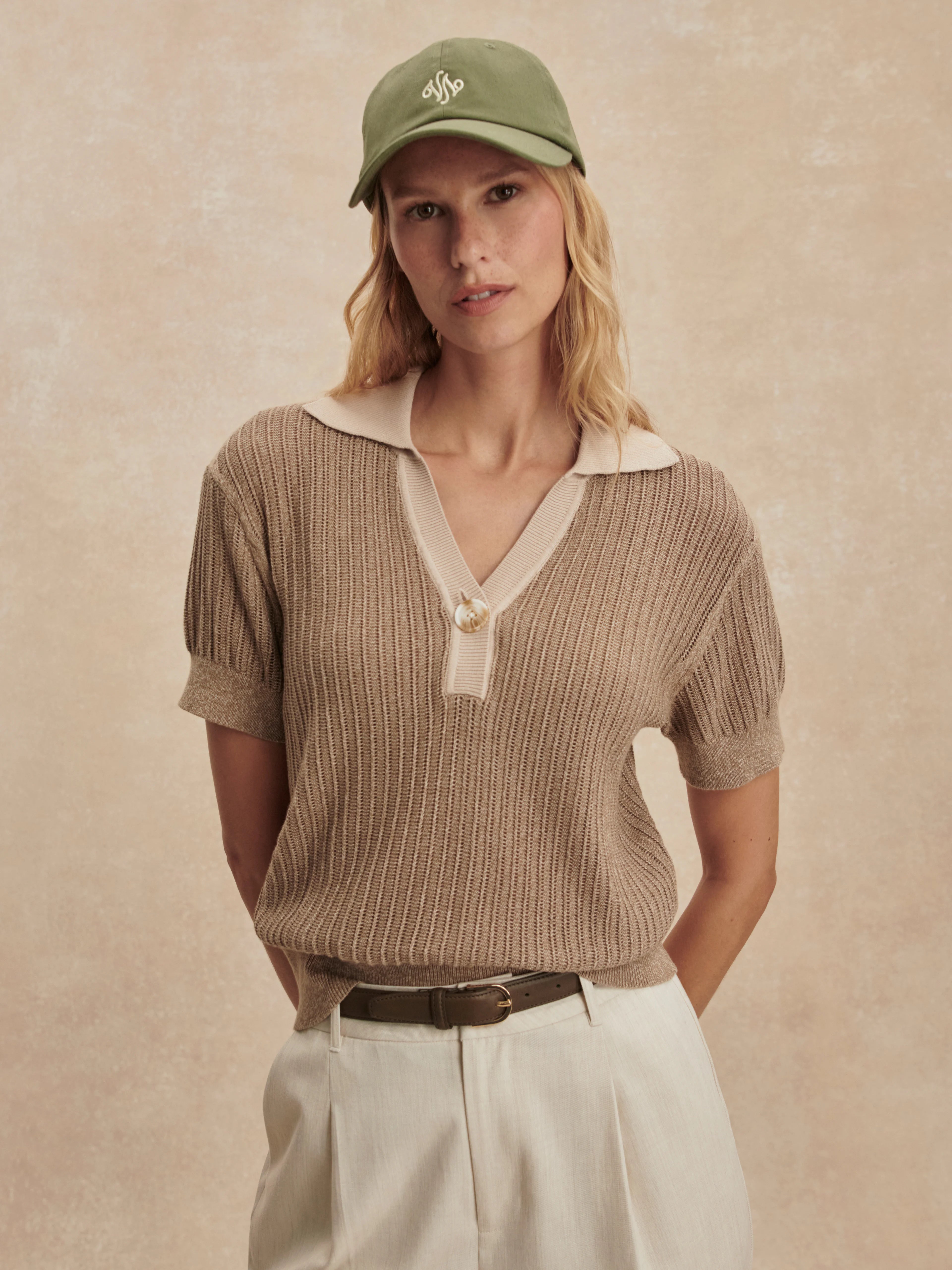 Tan ribbed knit short-sleeve polo with cream collar, v-neck, and single button closure.
