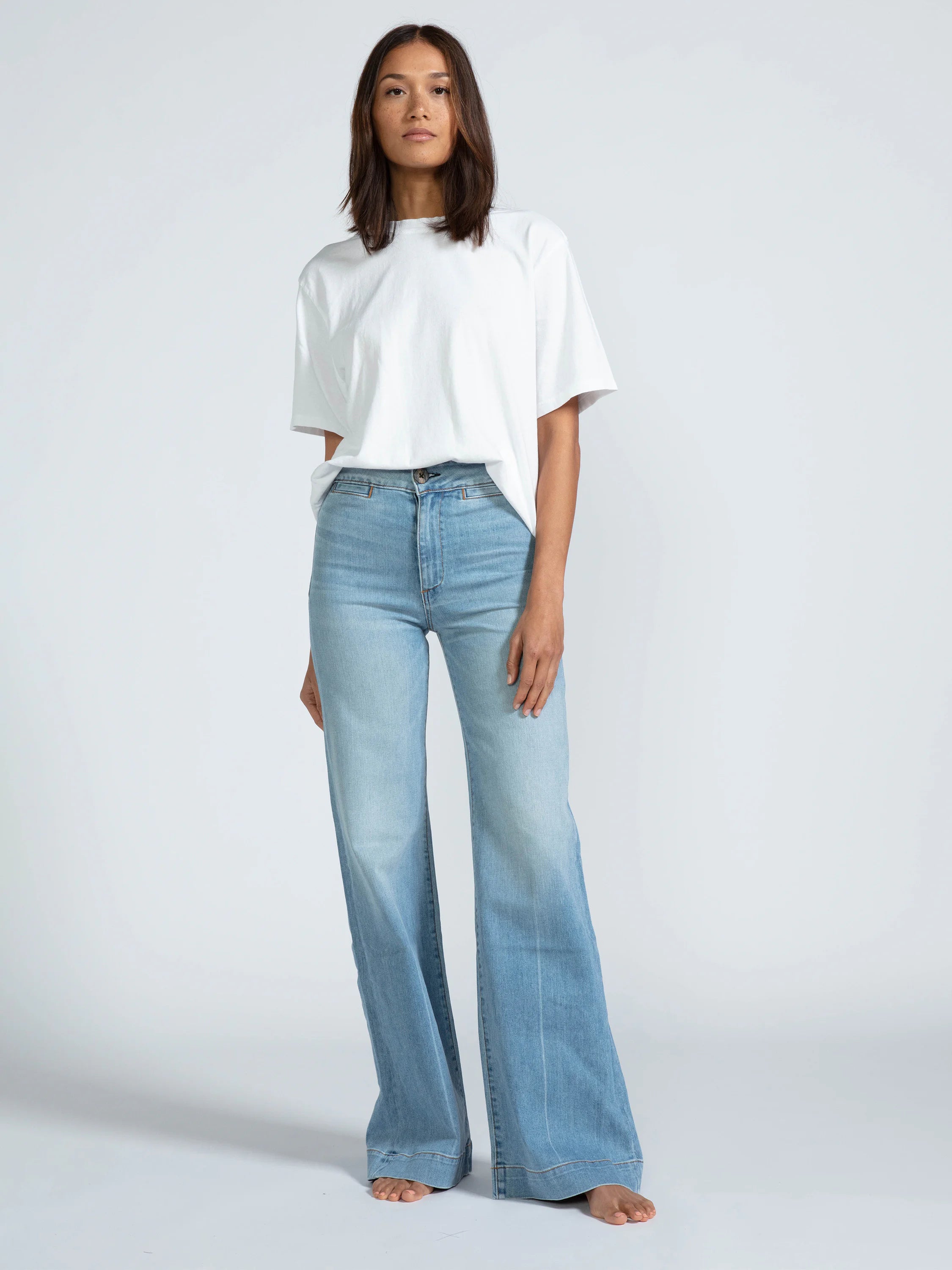 Light blue, wide-leg jeans; high-waisted with a straight leg that flares out at the ankle. The model is barefoot.