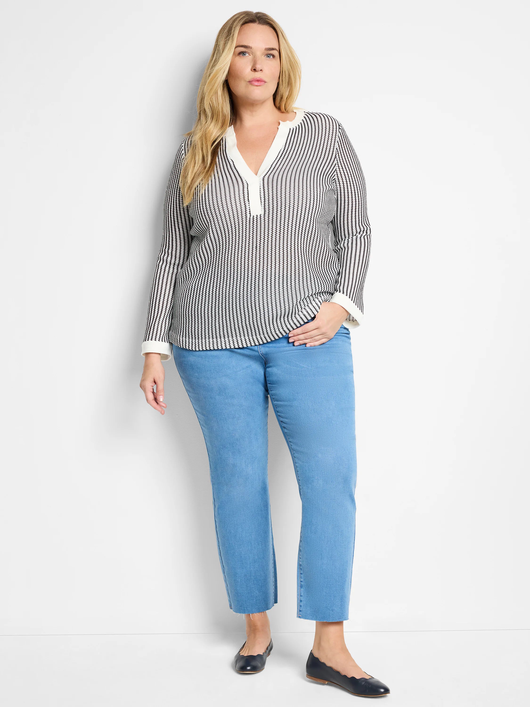 Off-white top with thin black vertical stripes, split neckline. Long sleeves with off-white cuffs.