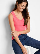 Bright coral ribbed knit scoop neck tank top on a model.