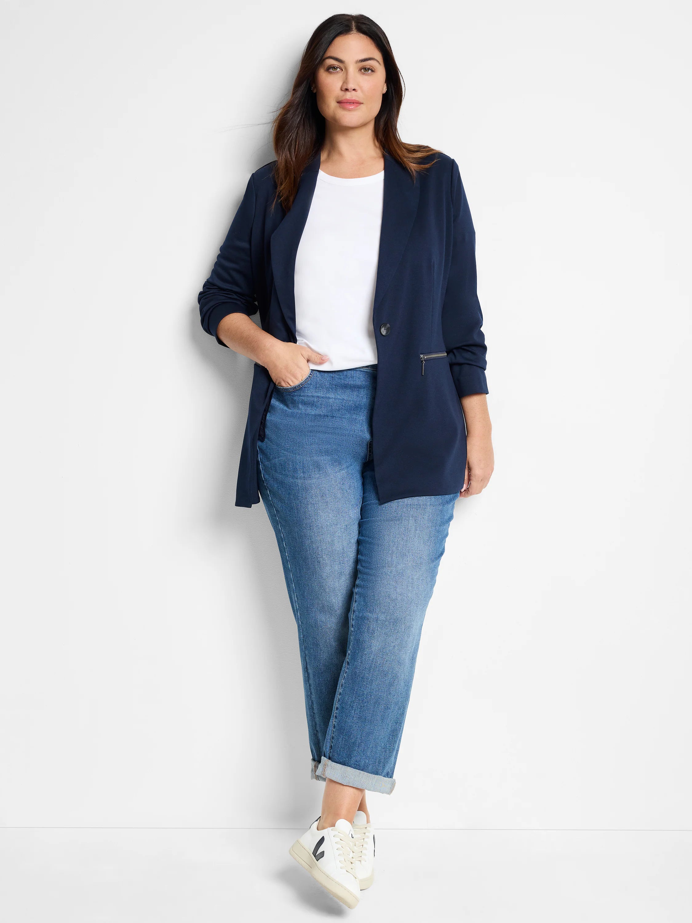 Navy blue zip-front jacket. Single button. Side zip detail. Shown on model with light wash jeans.