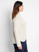 Off-white, long-sleeve top with subtle sparkle.  Shown on model with dark navy pants.