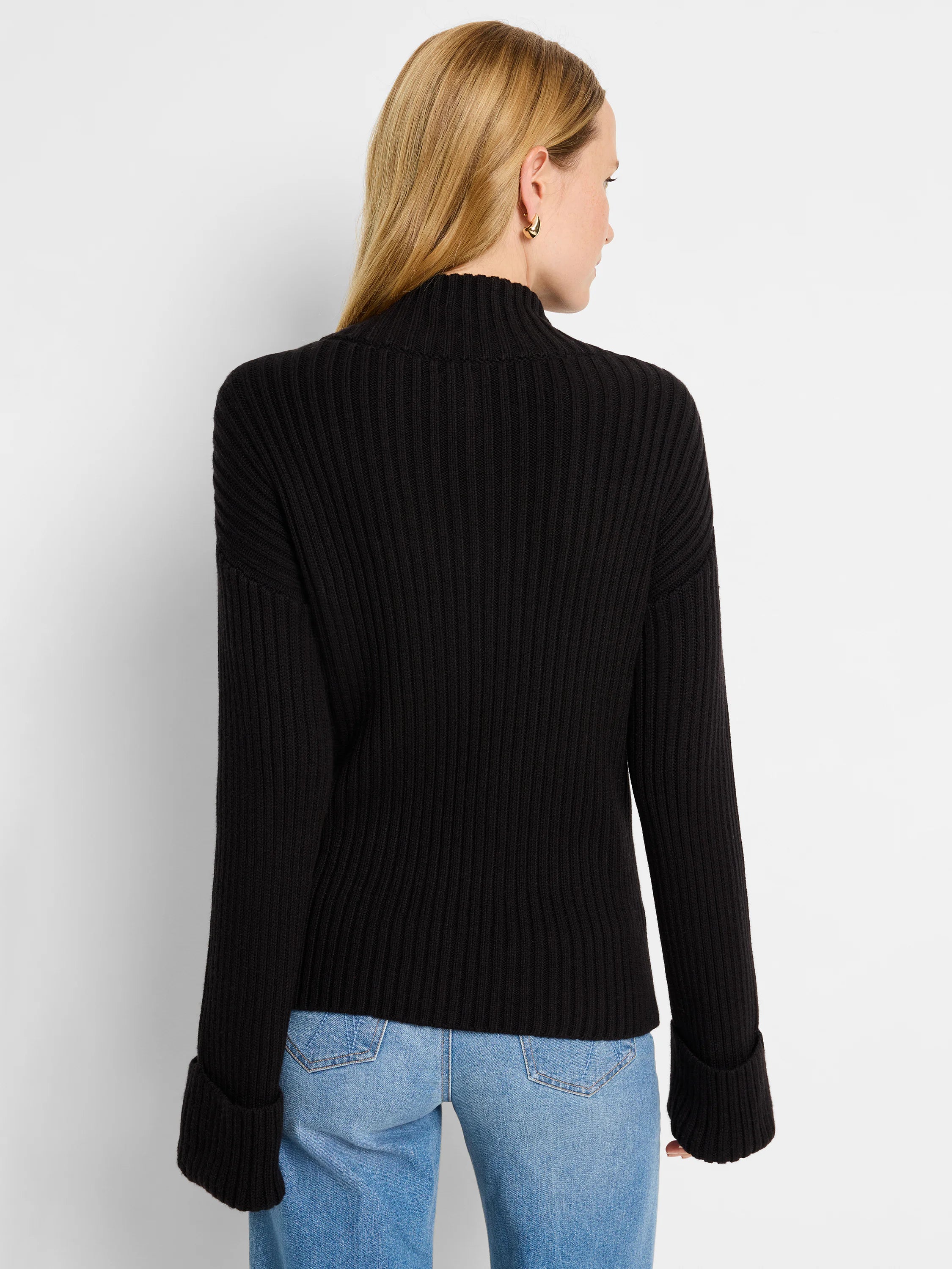 Black ribbed mock neck sweater with long sleeves and wide cuffs. Back view.