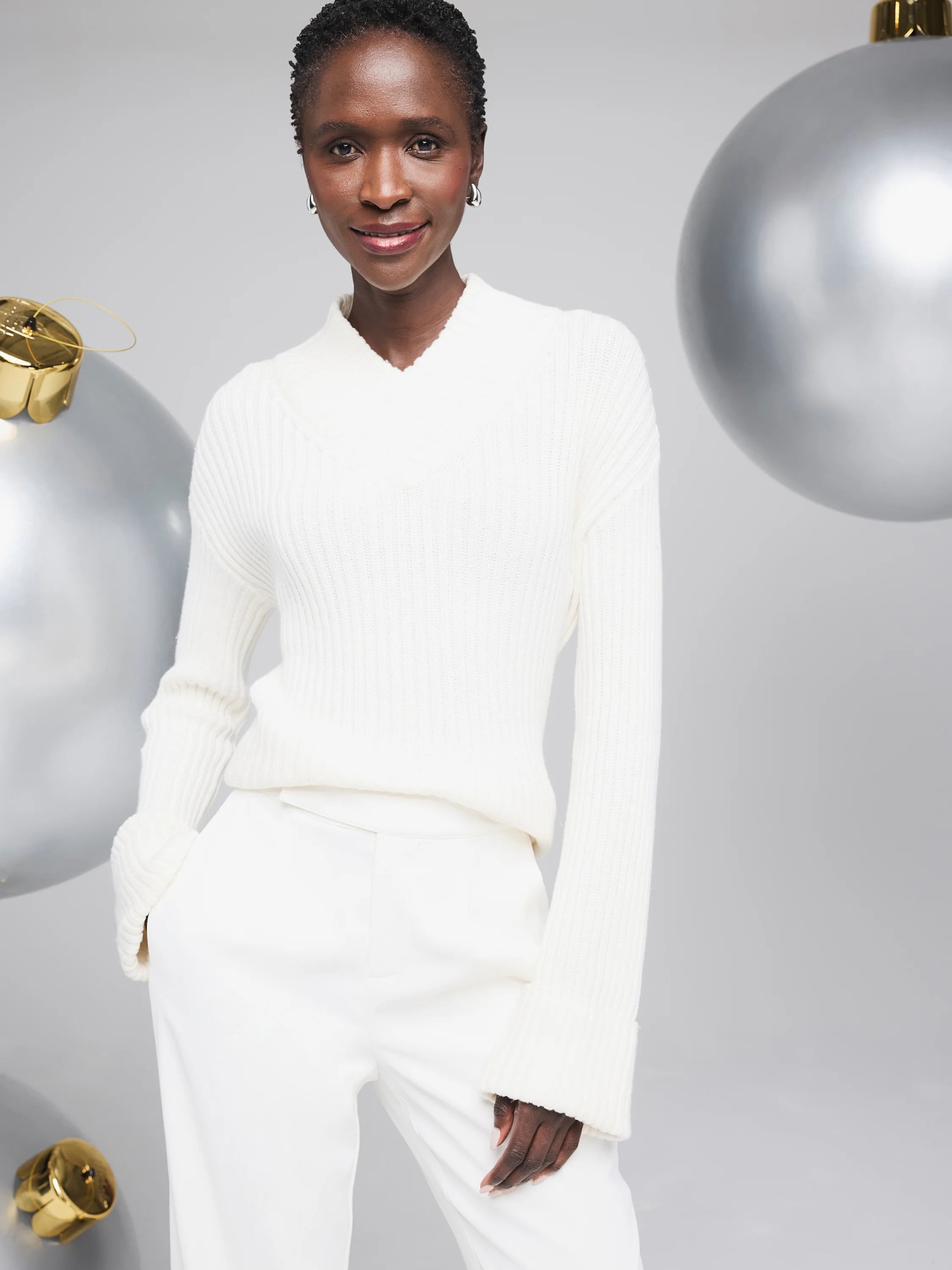 Off-white ribbed V-neck sweater. Long sleeves with ribbed cuffs. The sweater is shown on a model.
