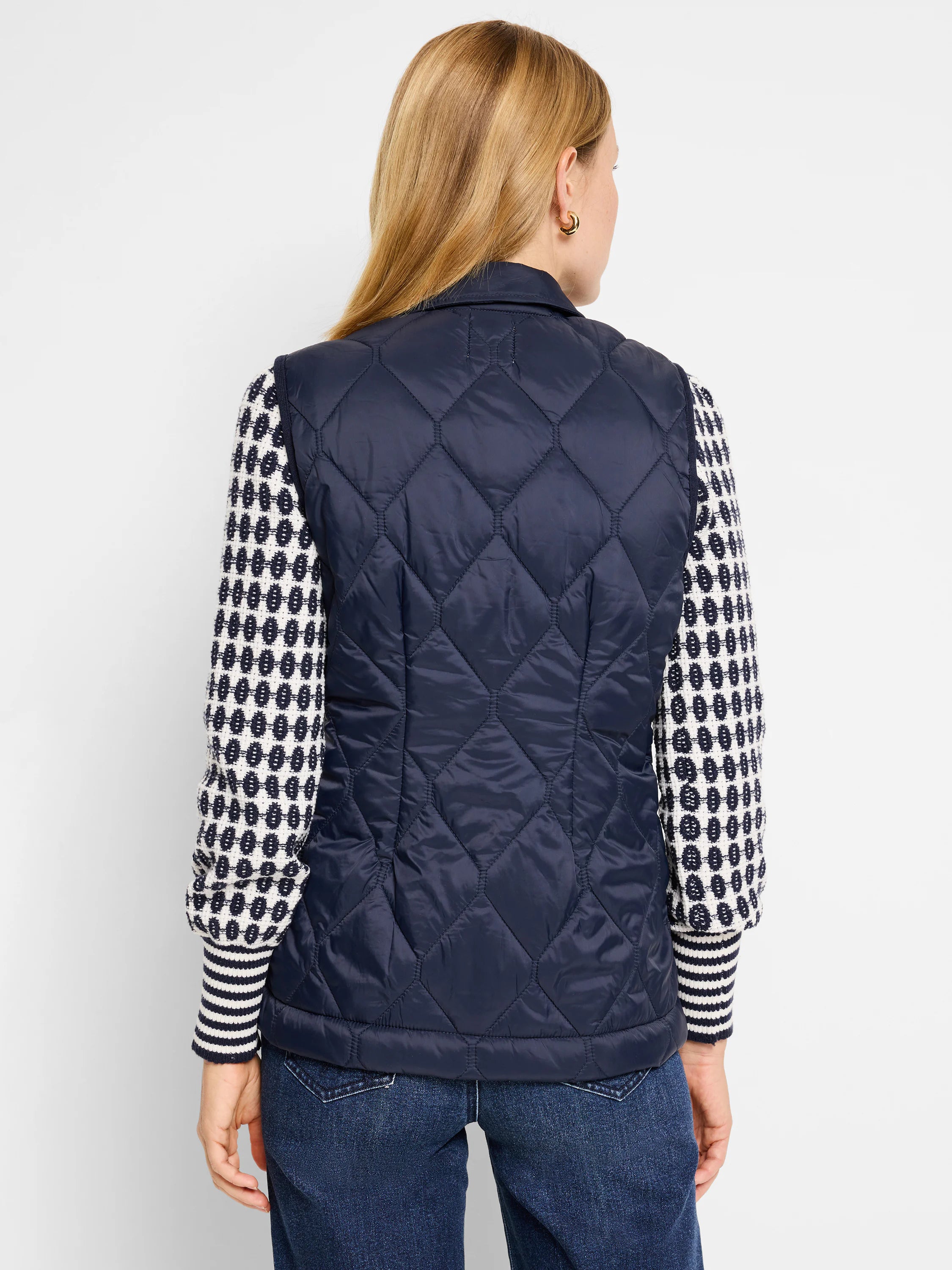 Navy blue quilted puffer vest. Diamond quilting pattern. Shown with a cream and navy patterned sweater.