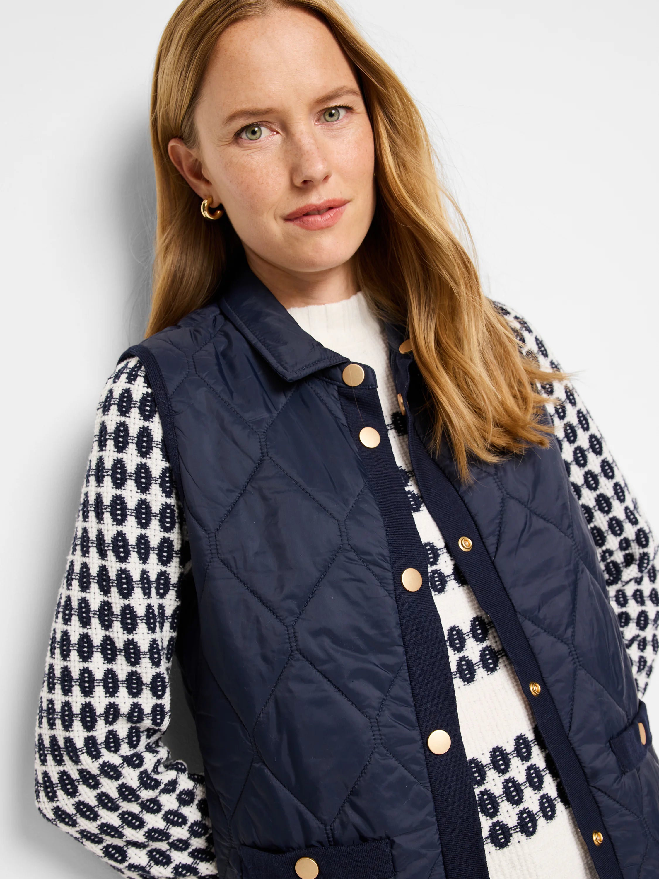 Navy blue quilted puffer vest with gold buttons and knit trim.