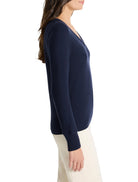 Navy blue V-neck sweater with long sleeves and ribbed cuffs, shown on a model from the side.