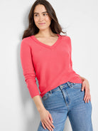 Coral pink garter knit V-neck sweater with long sleeves and ribbed cuffs, shown on a model.