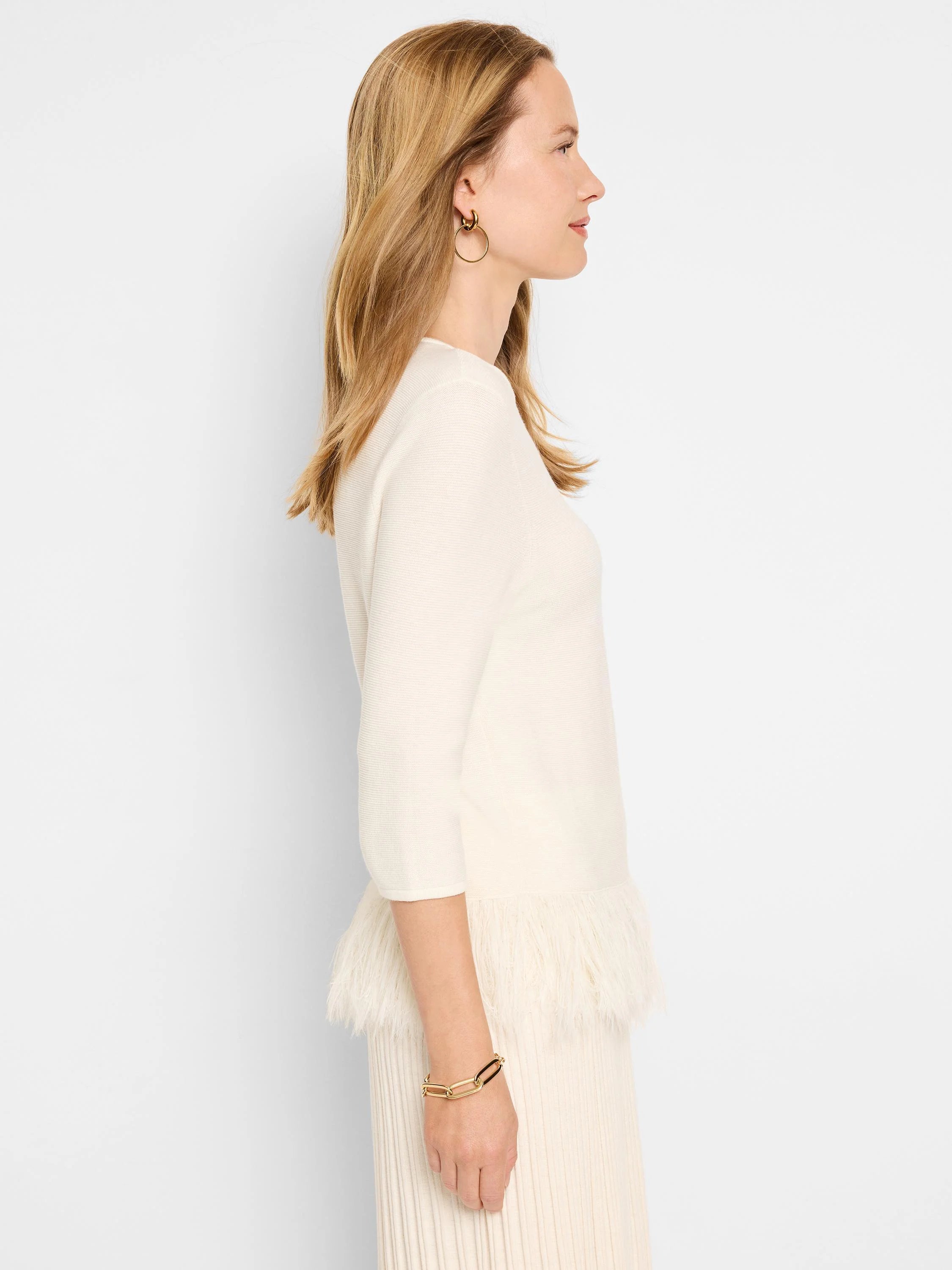 Off-white ribbed sweater with a feather fringe hem. Three-quarter sleeves.