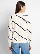 Off-white cardigan with diagonal navy stripes, long sleeves, and a relaxed fit.