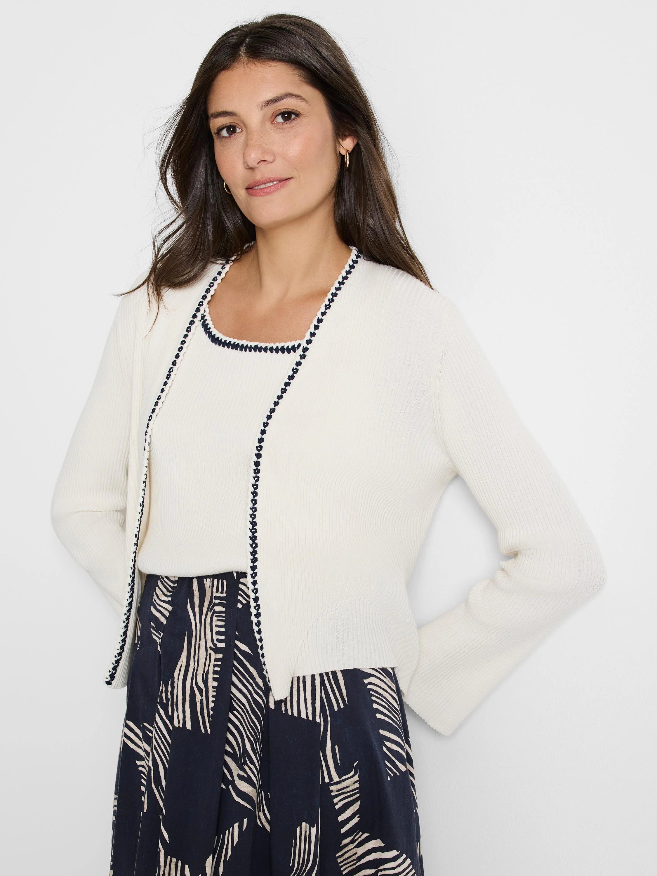 Off-white ribbed cardigan with dark navy trim. Long sleeves.