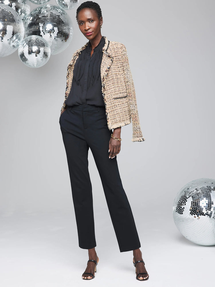 Beige tweed jacket with black chain trim and frayed edges. Model wears it over a black top.