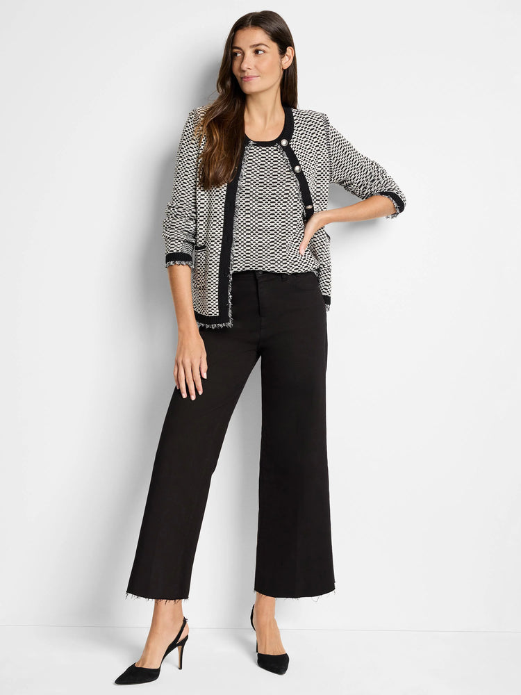 Black and white patterned sweater jacket with black trim and frayed edges. The model is wearing black pants and shoes.