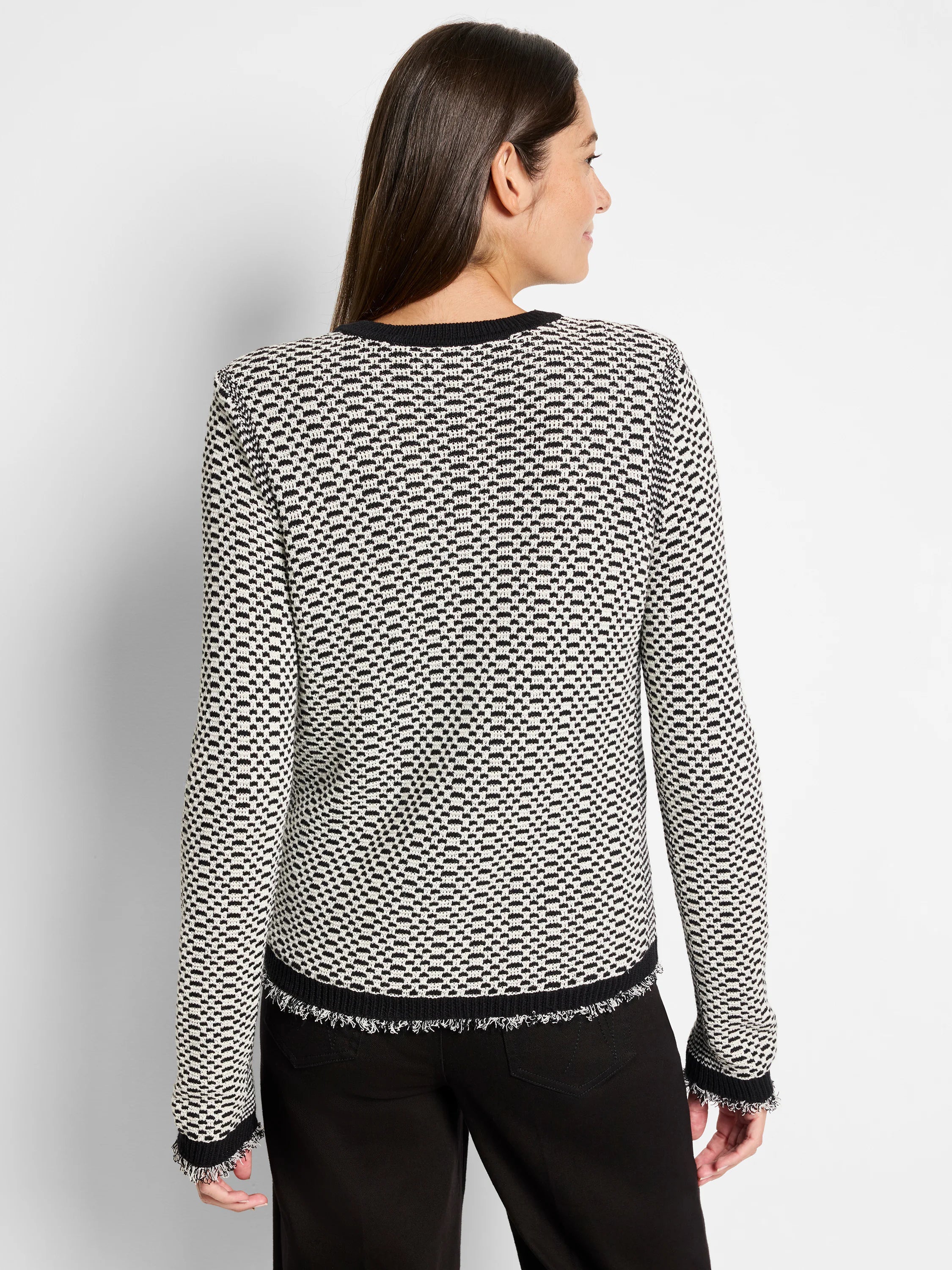 Off-white sweater jacket with black geometric pattern and frayed edges.  Black trim at neckline and cuffs.