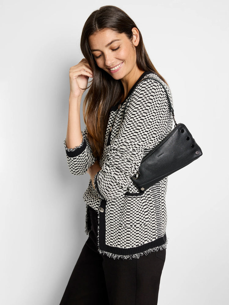 Black and off-white patterned sweater jacket with frayed edges. Model also carries a black leather handbag.