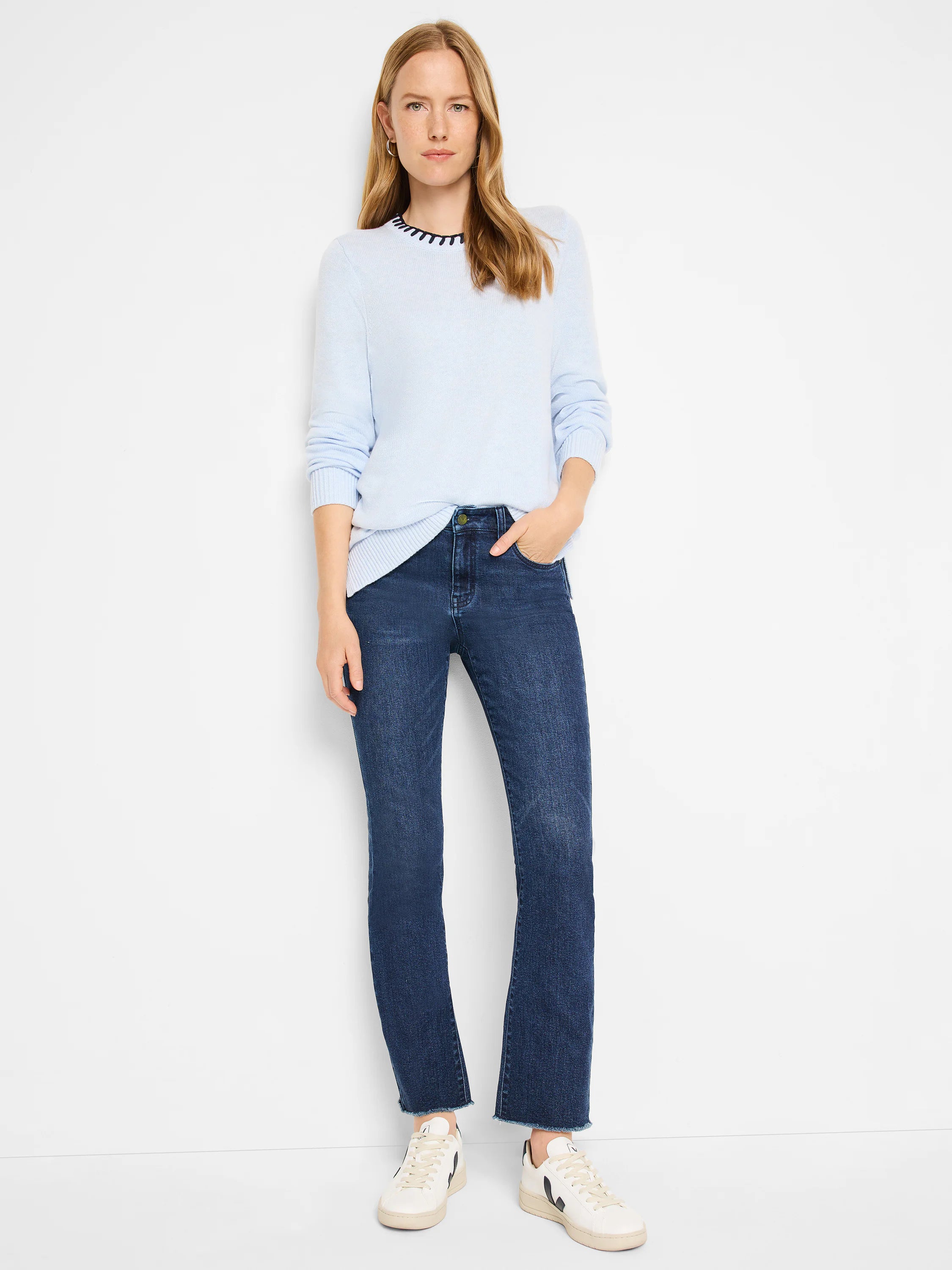 Light blue crewneck sweater with dark trim, shown with dark wash jeans and white sneakers.