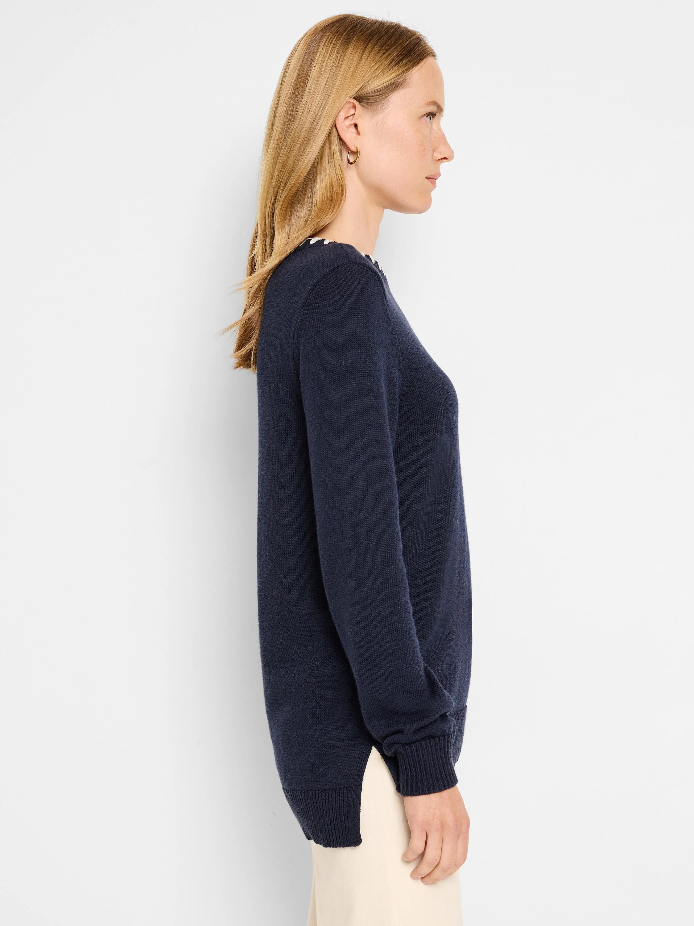 Dark navy blue long-sleeved sweater.  Small off-white detail at neckline. Side slits. Knit texture.