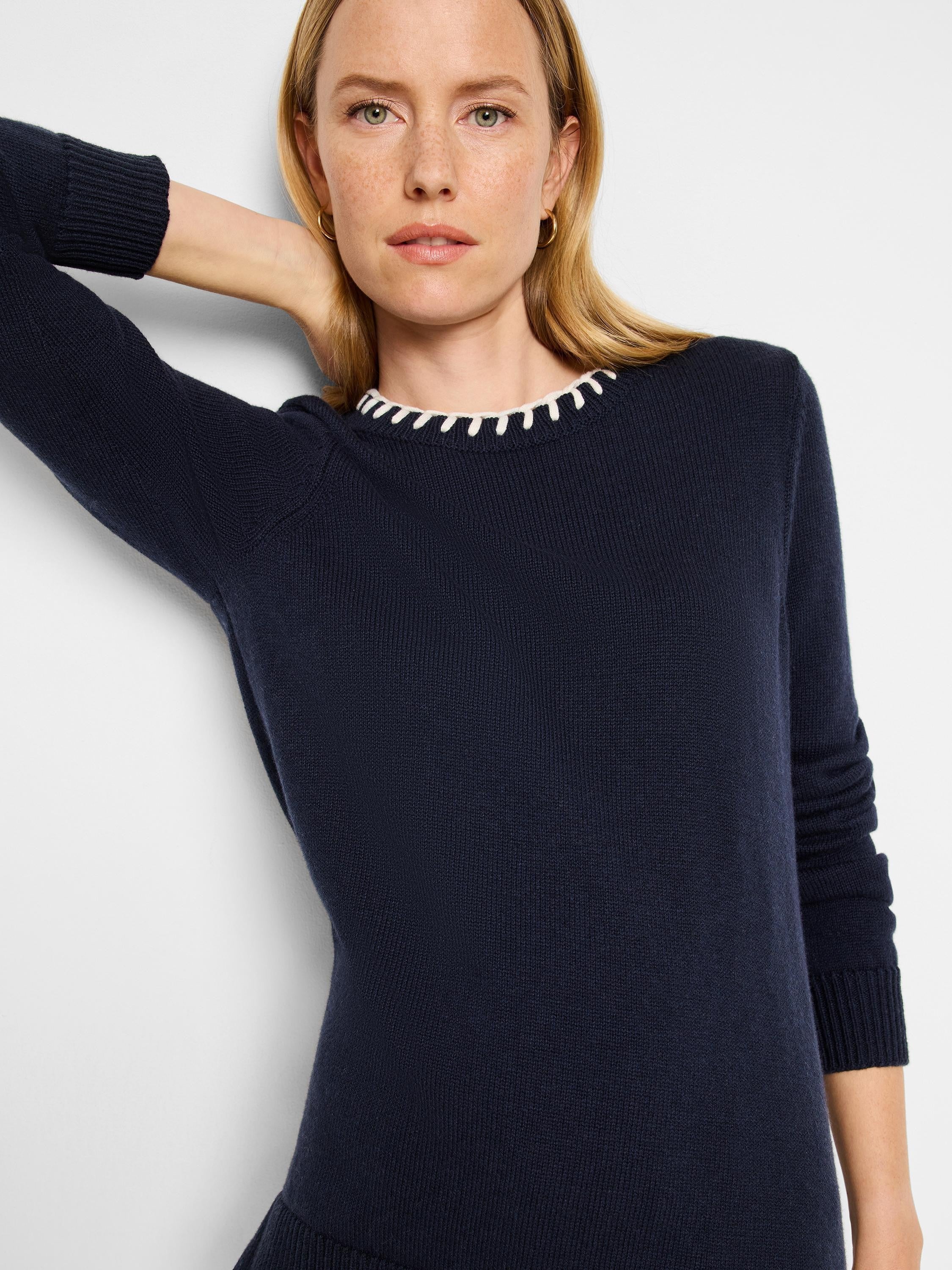 Navy blue sweater with off-white trim at neckline. Long sleeves, knit fabric.