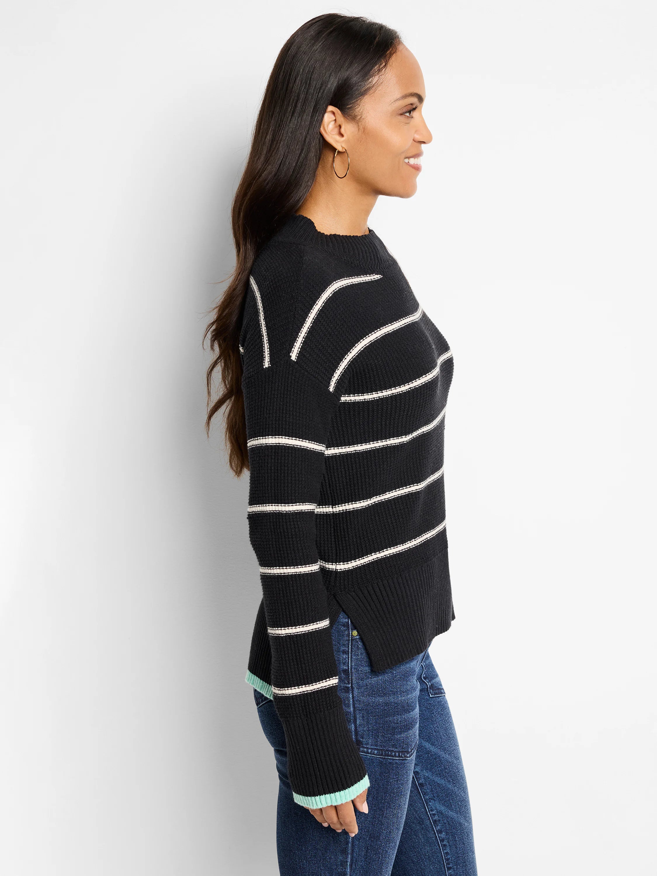 Black waffle-knit sweater with thin off-white stripes and light teal cuffs.