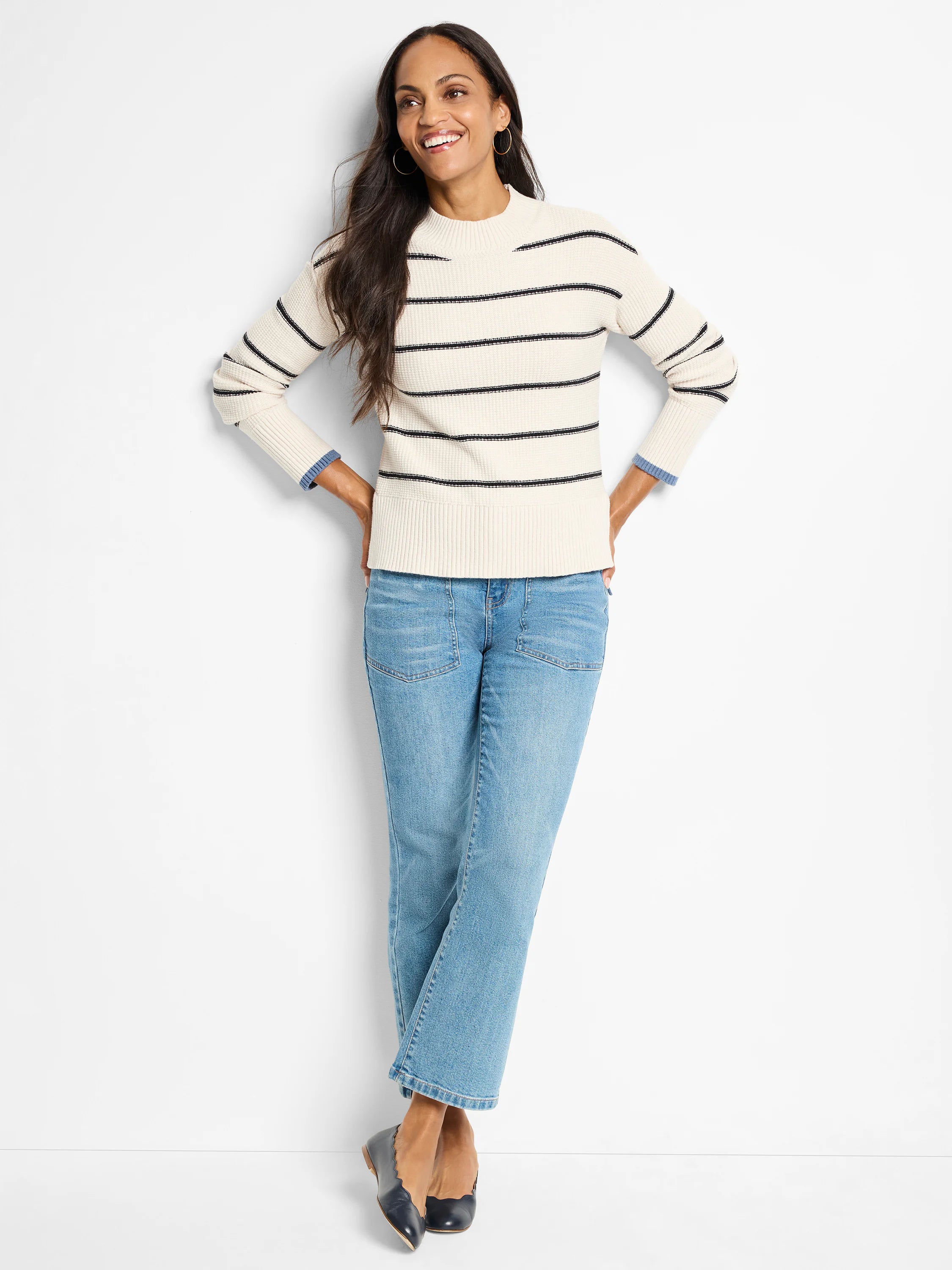 Cream waffle-knit sweater with thin dark stripes; mock neck.