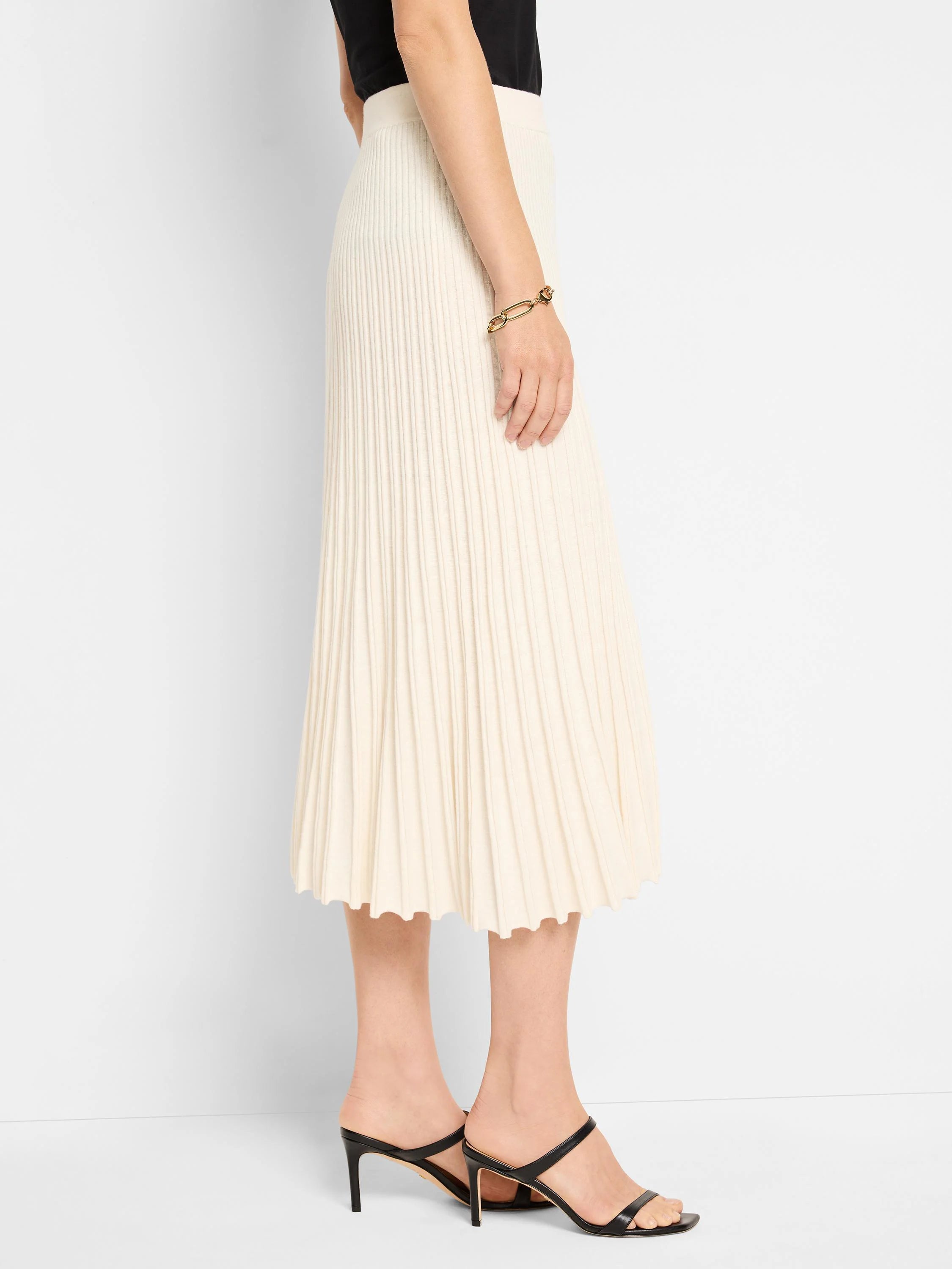 Cream ribbed knit midi skirt with a pleated look and wavy hem.
