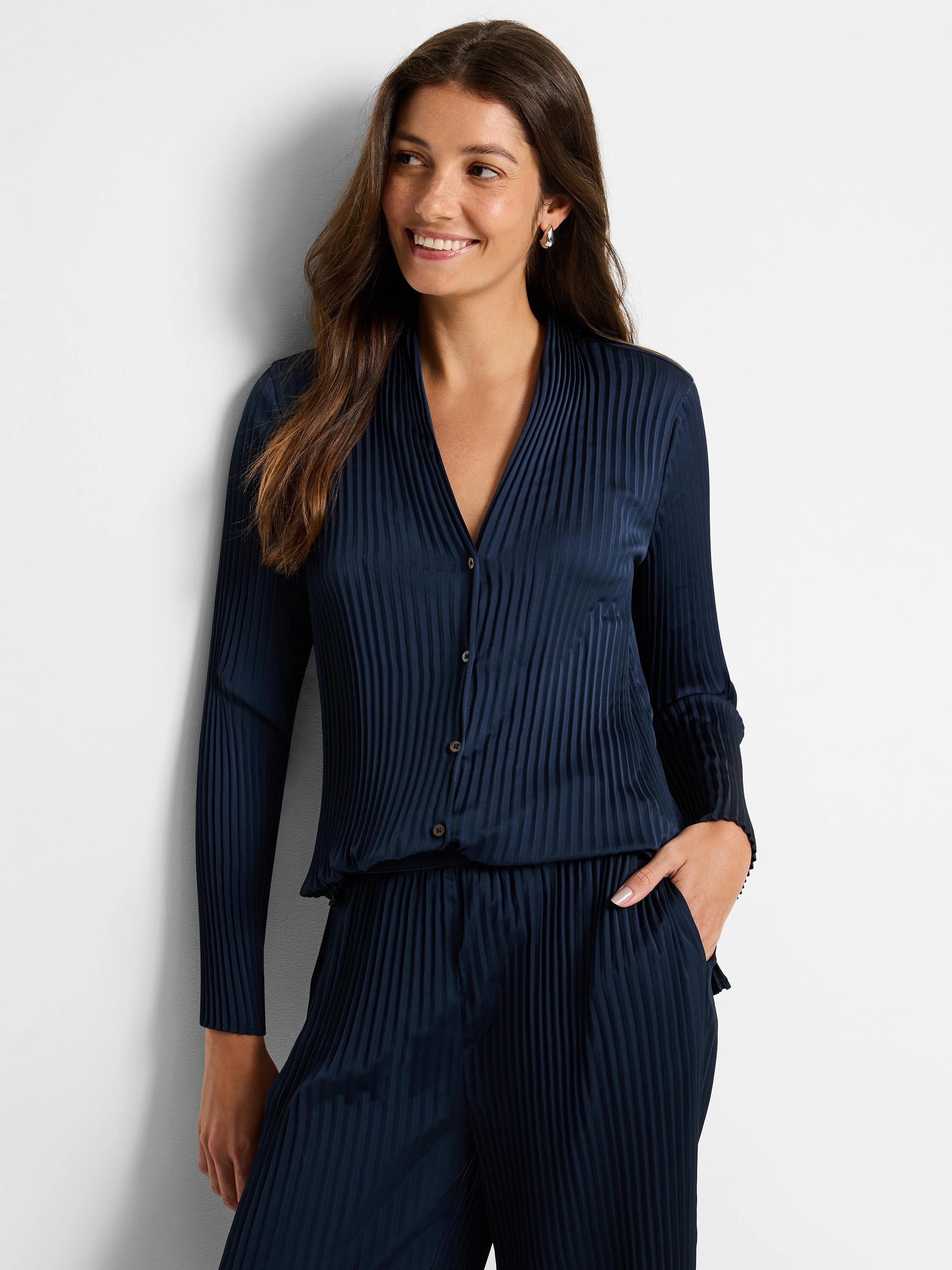 Navy blue, vertically pleated long-sleeve shirt with button closure. Matching pleated pants shown.