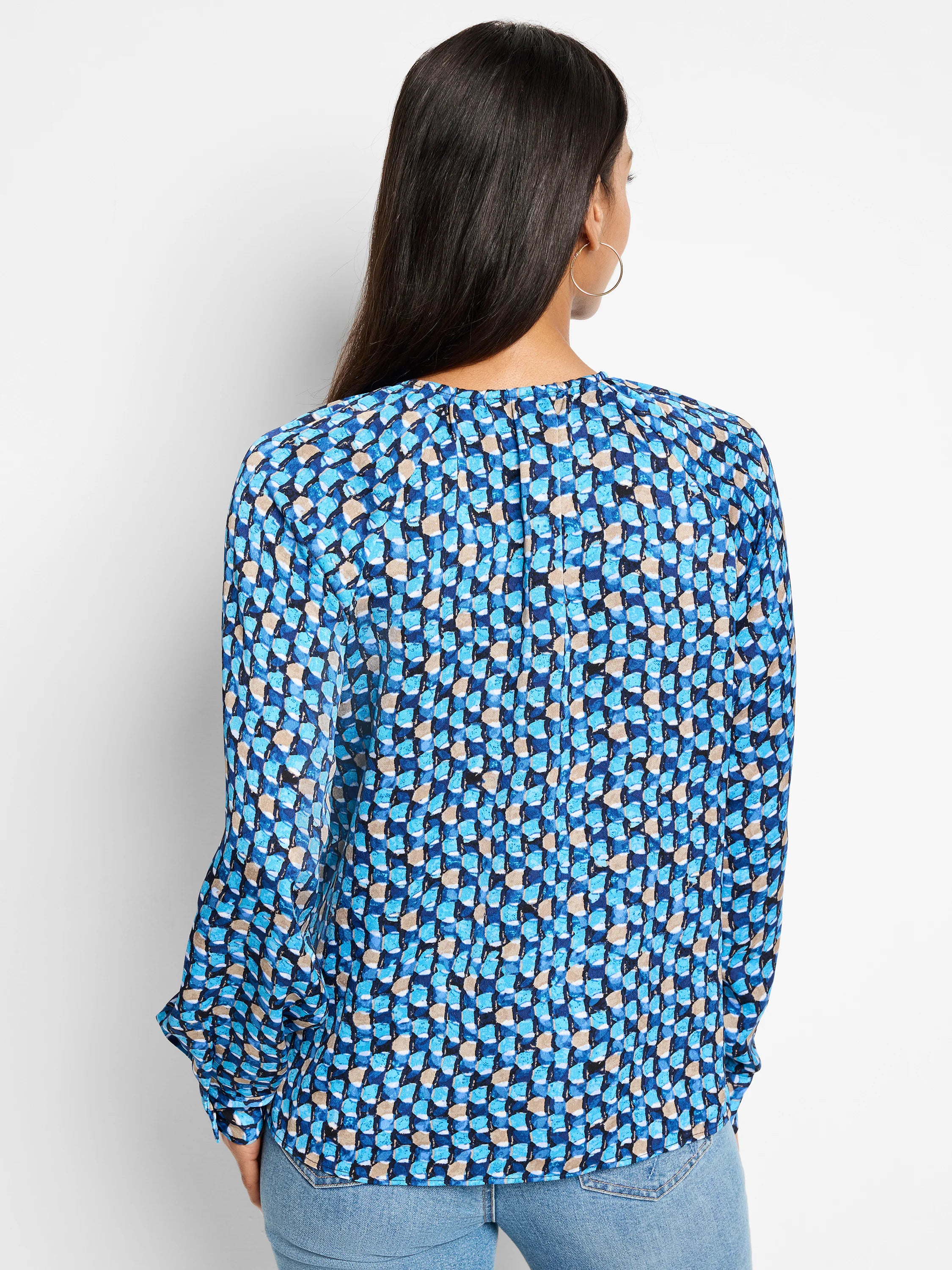 Long-sleeve blue top with a repeating abstract pattern in shades of blue, beige, and black. Back view.